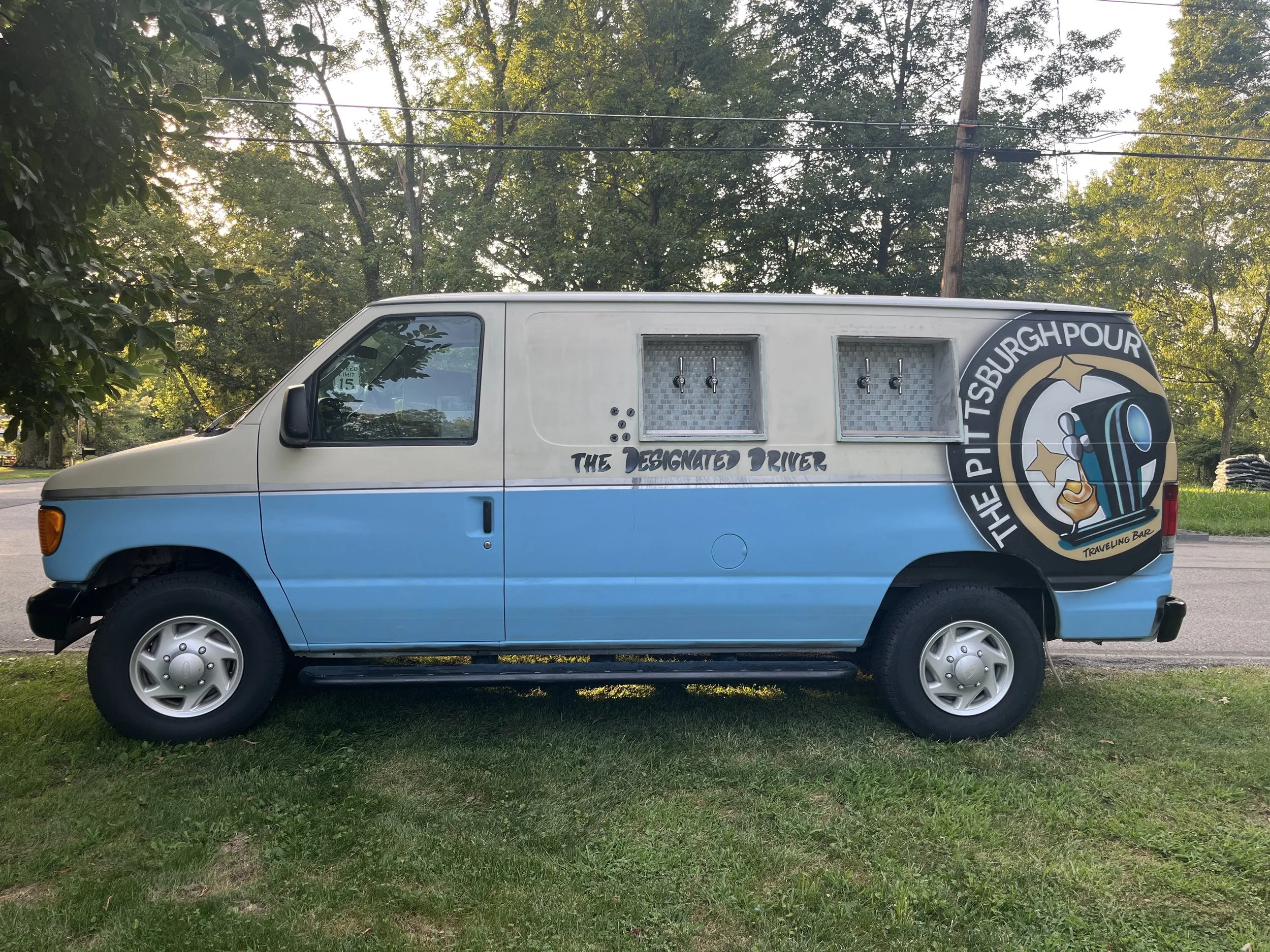 A van with a graphic design of a pint glass pouring beer and the text 'The Pittsburgh Pour' with the tagline 'Traveling Bar'.