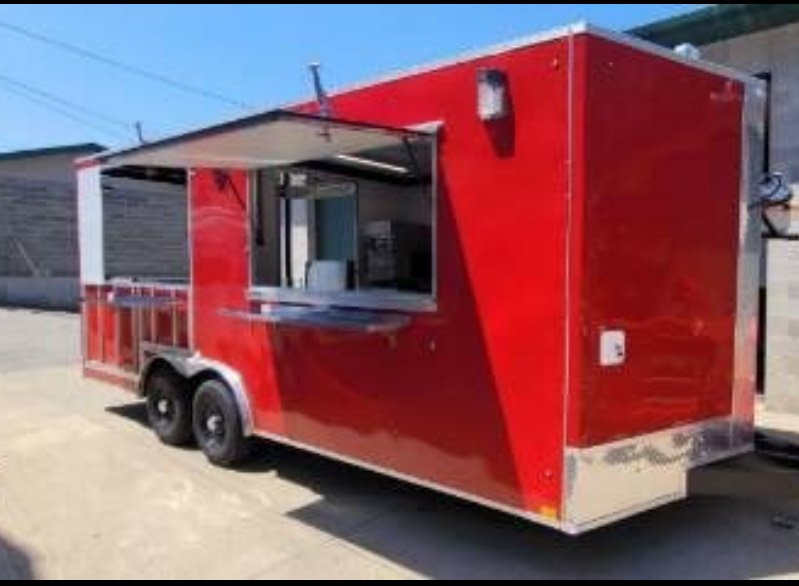 Red food truck with a side window serving area and a small service counter, parked outdoors on a dirt surface.