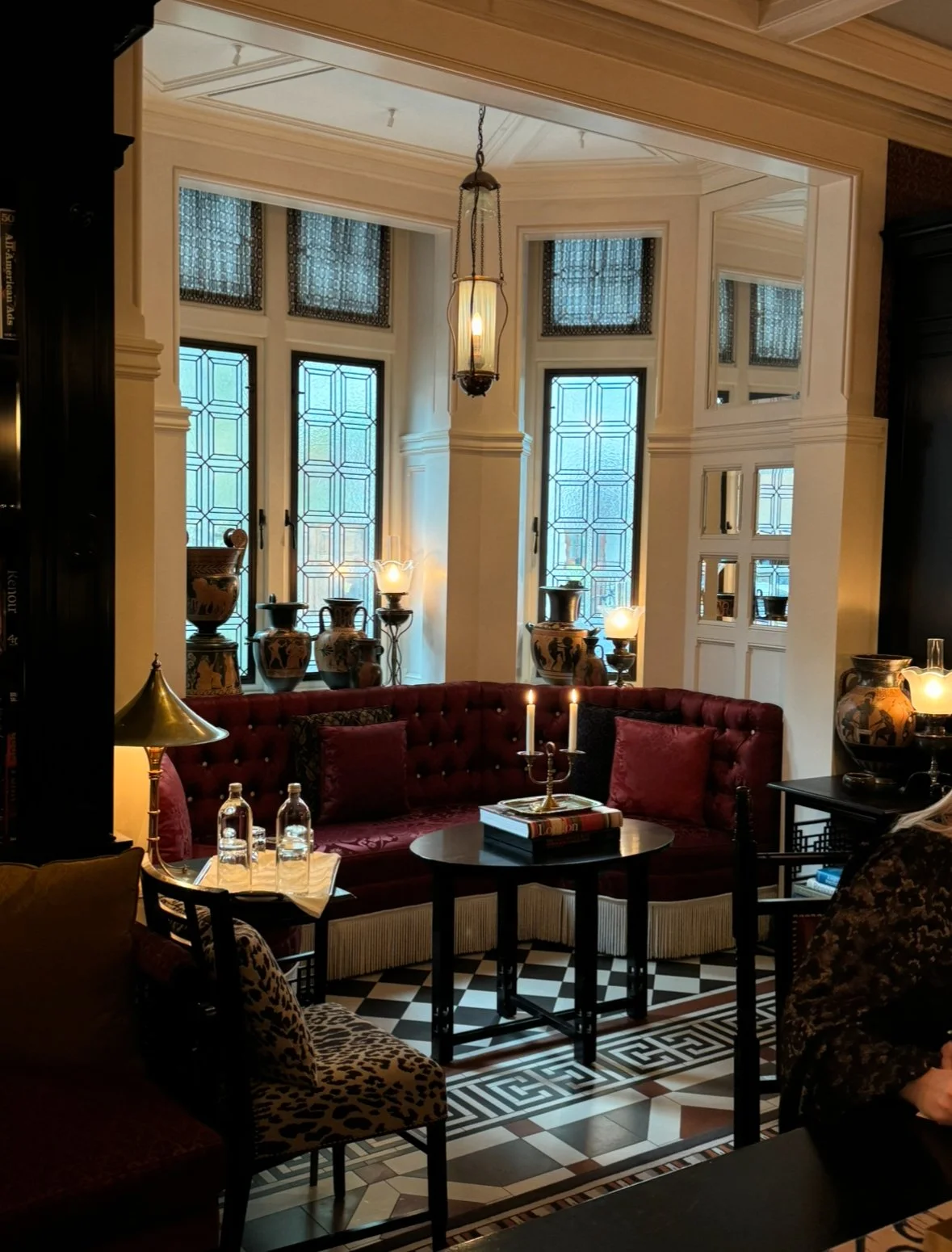Beautifully decorated ground floor of At Sloane hotel, art deco style furniture, velvety armchairs, and candlelight.