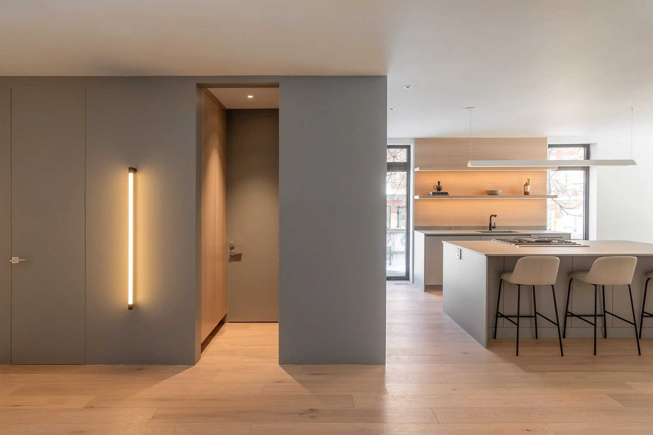 Cuisine moderne avec îlot central et corridor minimaliste du projet Résidence JM conçu par Ateliers Royer.