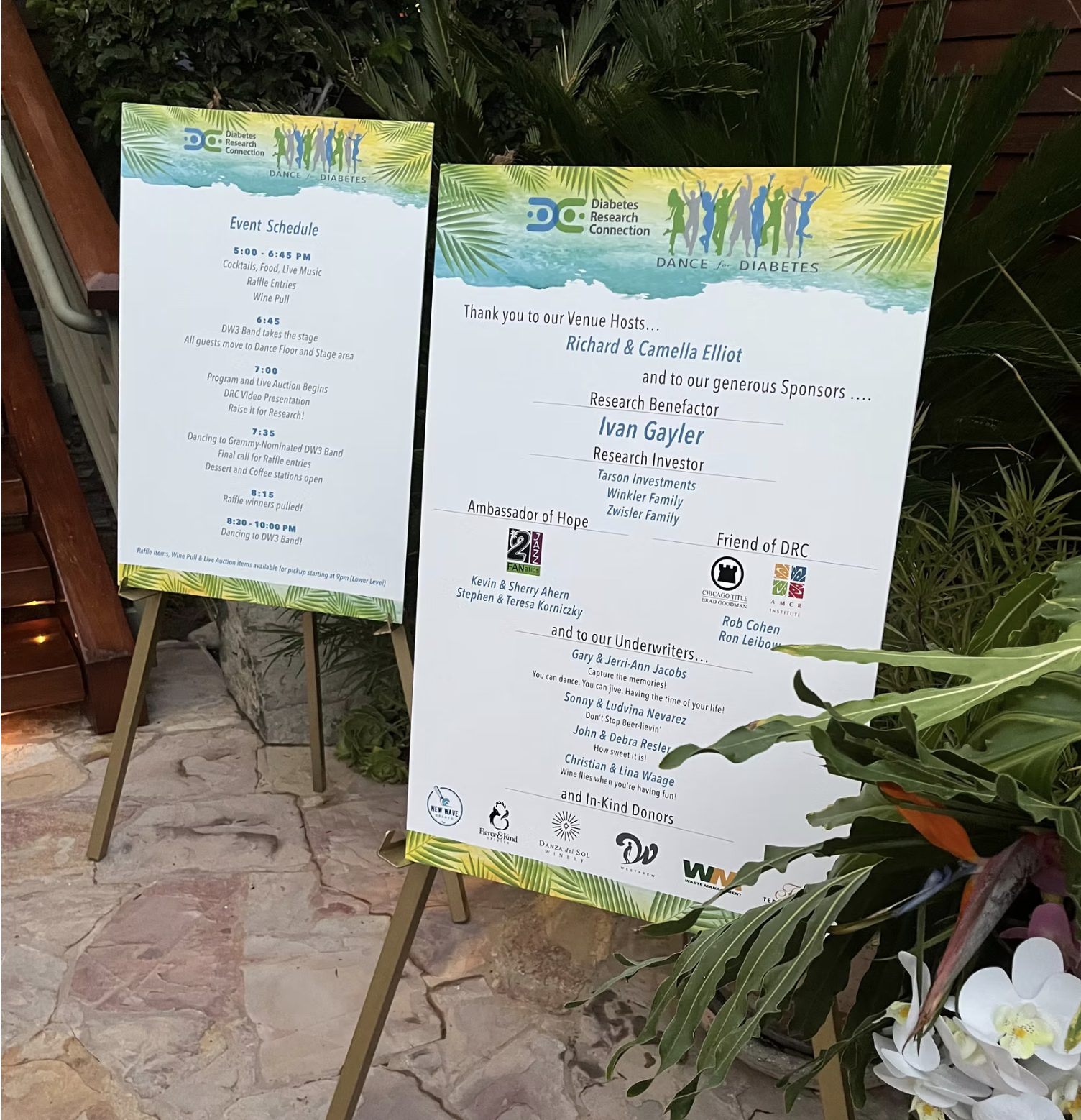Two event signage boards with information on the Diabetes Research Connection gala, including event schedule and list of sponsors, displayed outdoors next to plants.