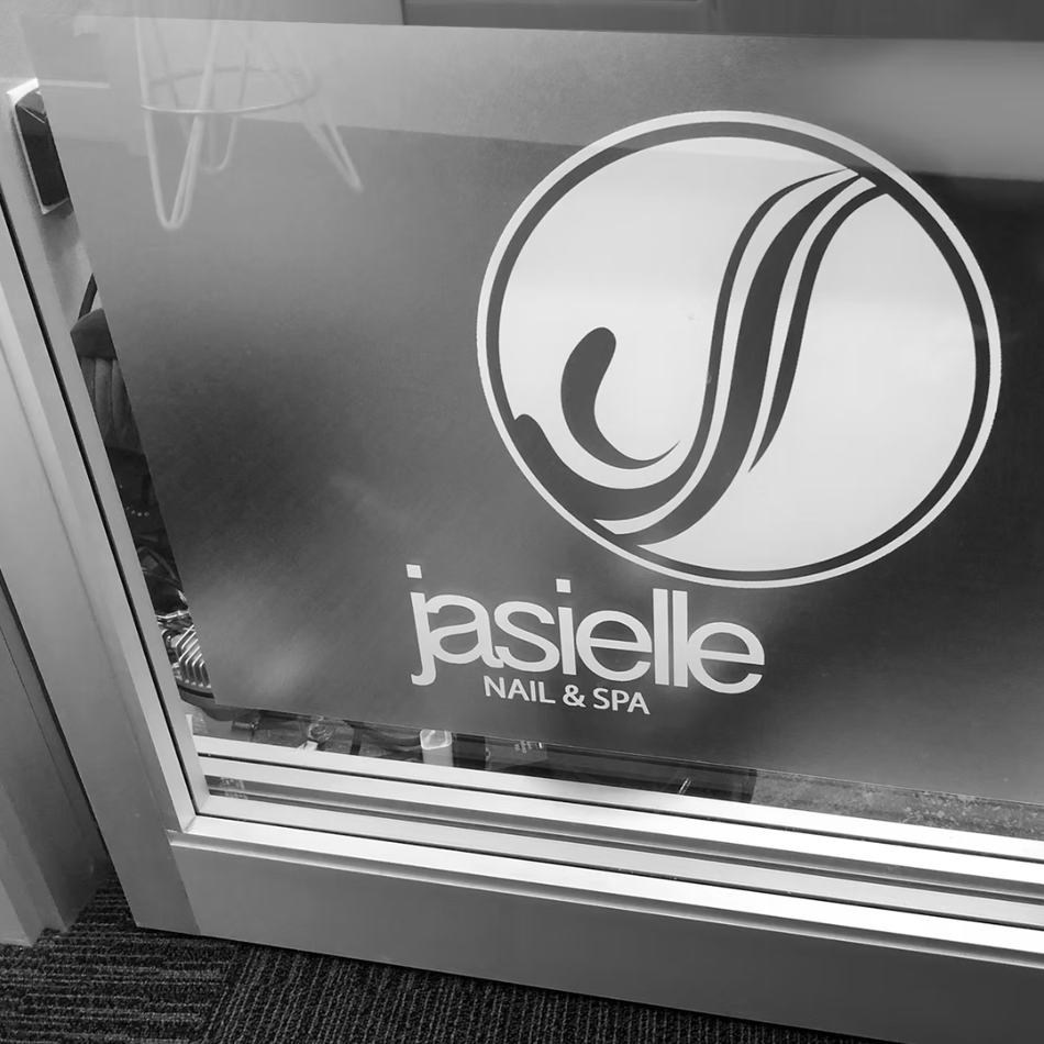 Jasielle Nail & Spa storefront sign with logo on a glass door.