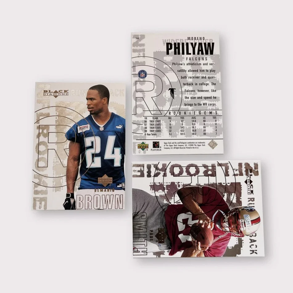 Three football rookie cards featuring players in jerseys, with one card showing player stats and information.