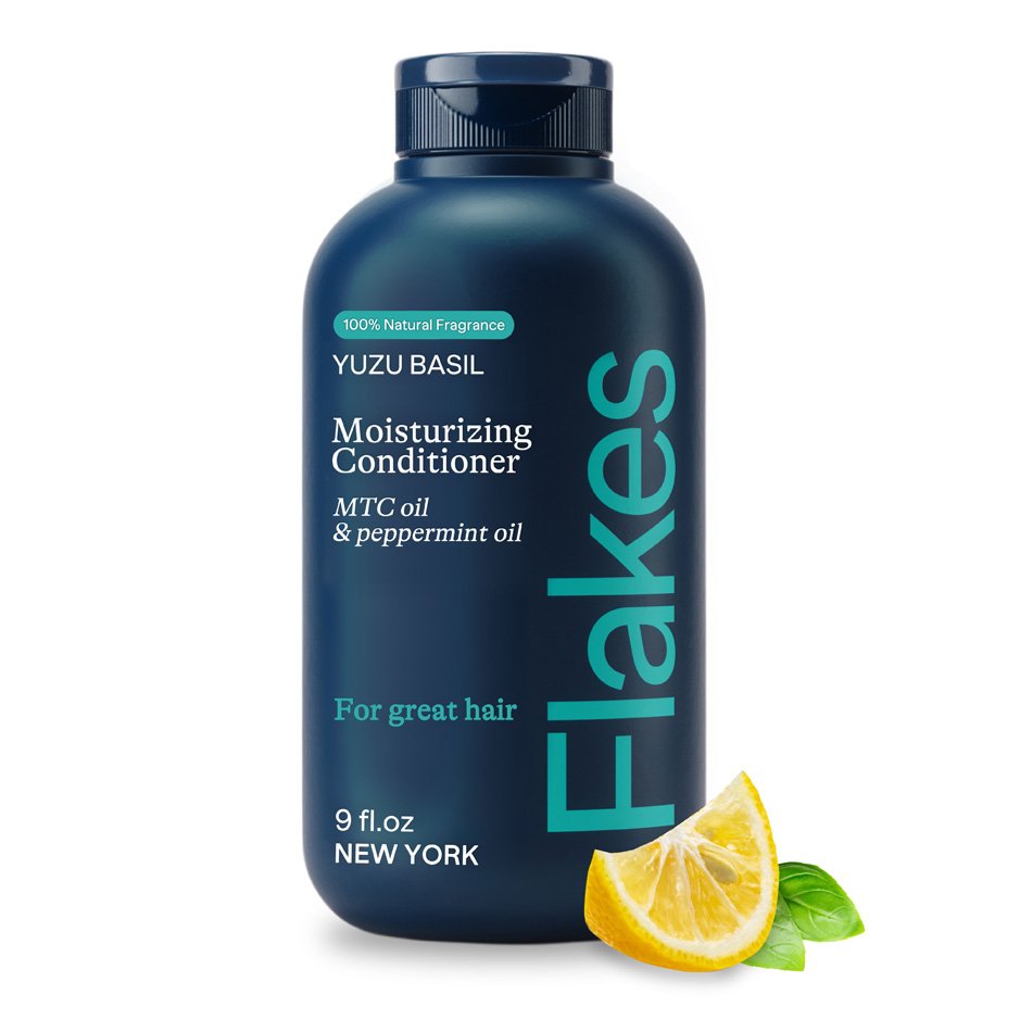 Dark blue bottle of Flakes Yuzu Basil Moisturizing Conditioner with MTC oil and peppermint oil, 9 fl. oz, with a lemon wedge and basil leaves.