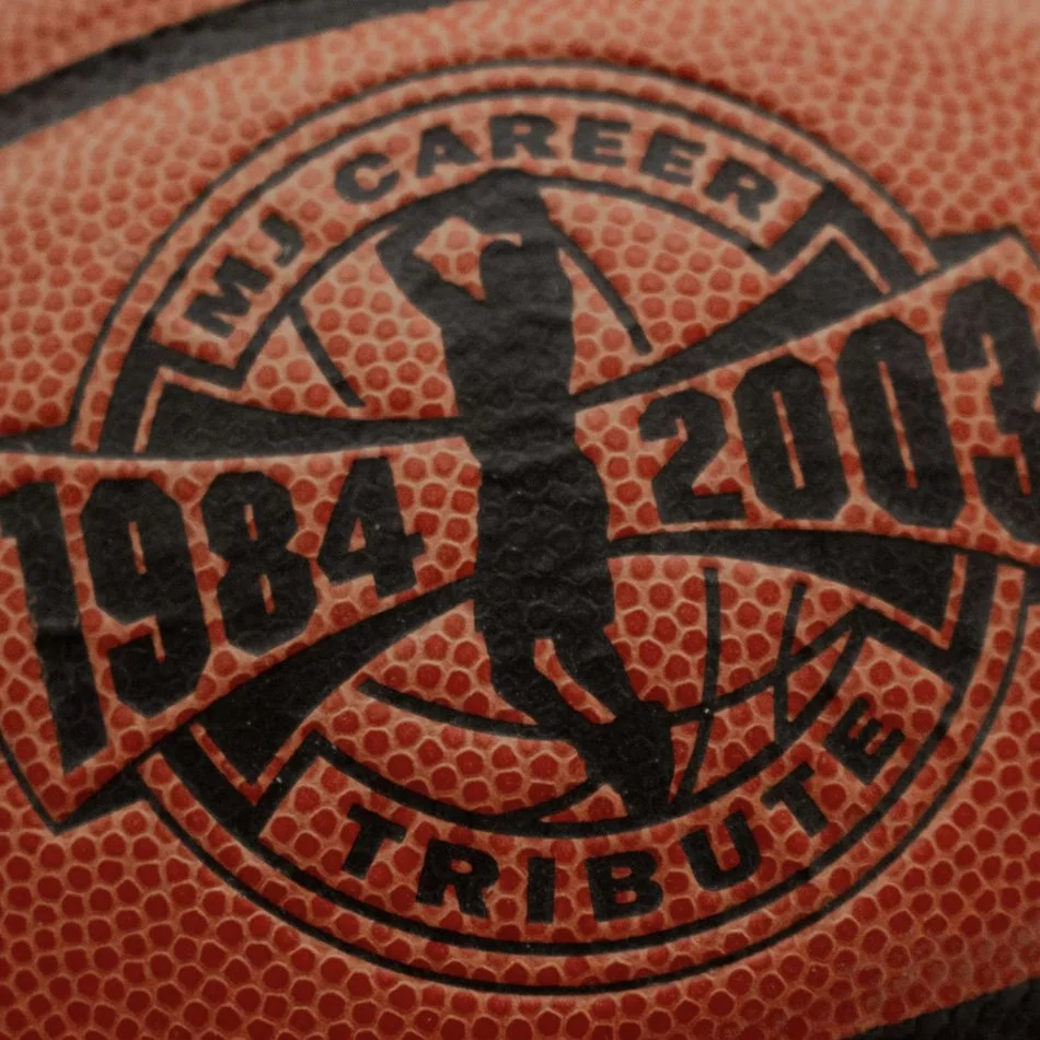 Close-up of a basketball embossed with text "MJ Career Tribute 1984-2003" featuring a silhouette of a player shooting.