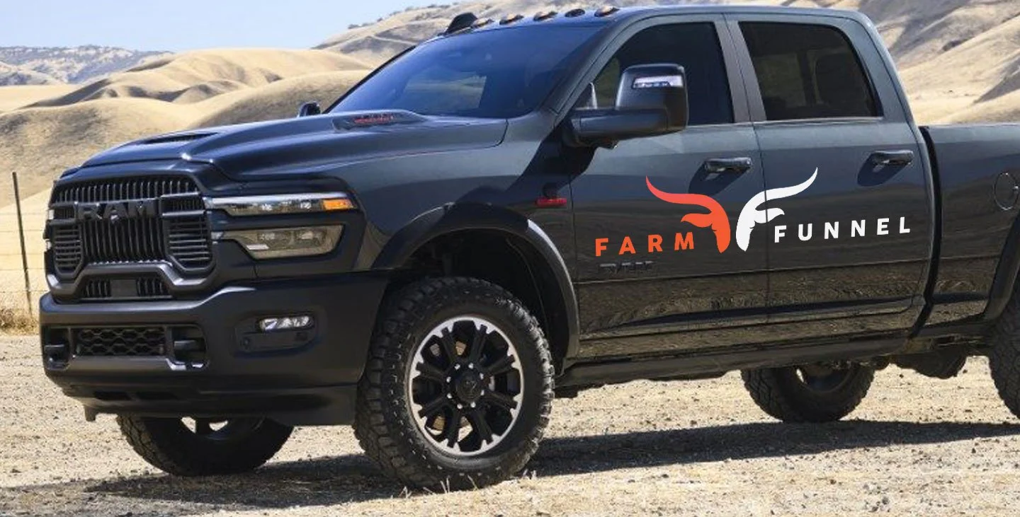 Black Ram pickup truck with Farm Funnel logo on the side, parked on dirt ground in a desert landscape with rolling hills and mountains in the background.