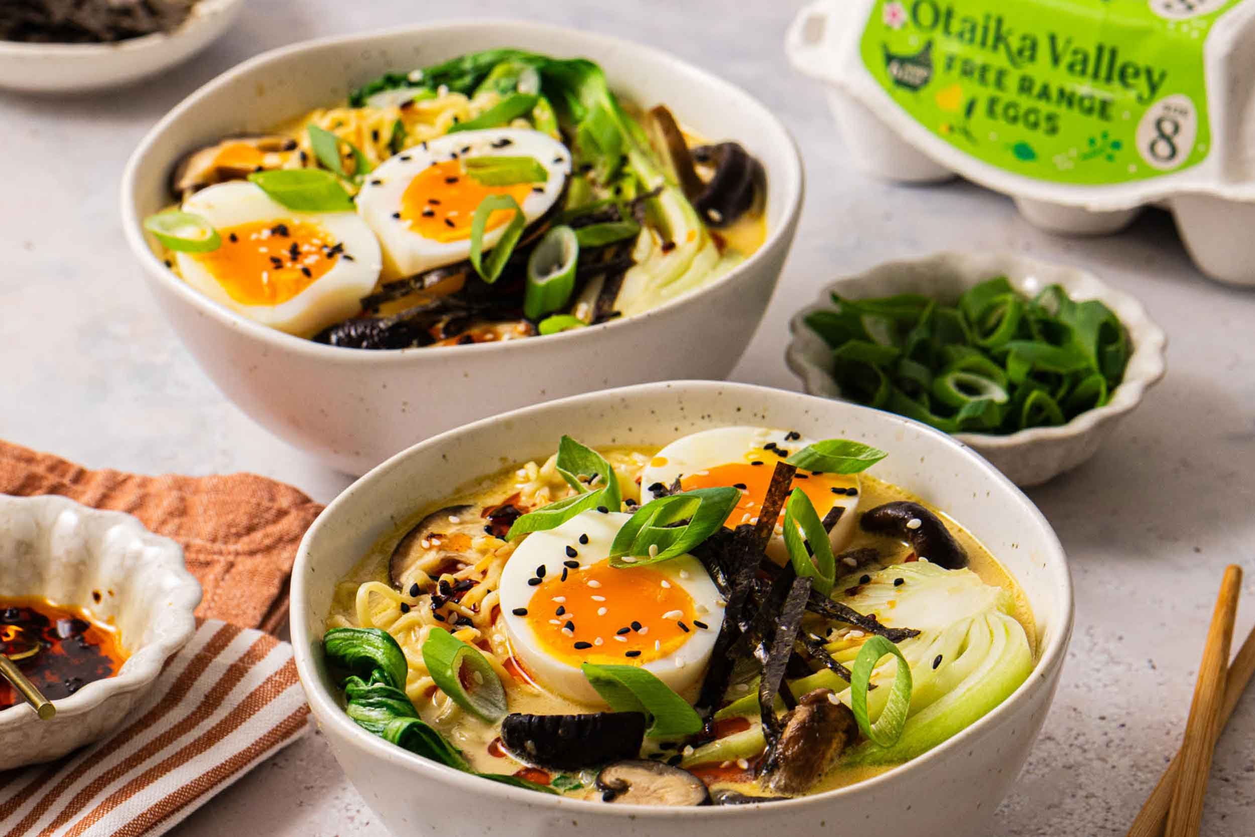 Two bowls filled with Ramen topped with jammy eggs, shiitake mushrooms, bok choy and spring onions