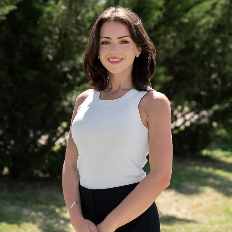 Smiling woman in gray suit against black background.