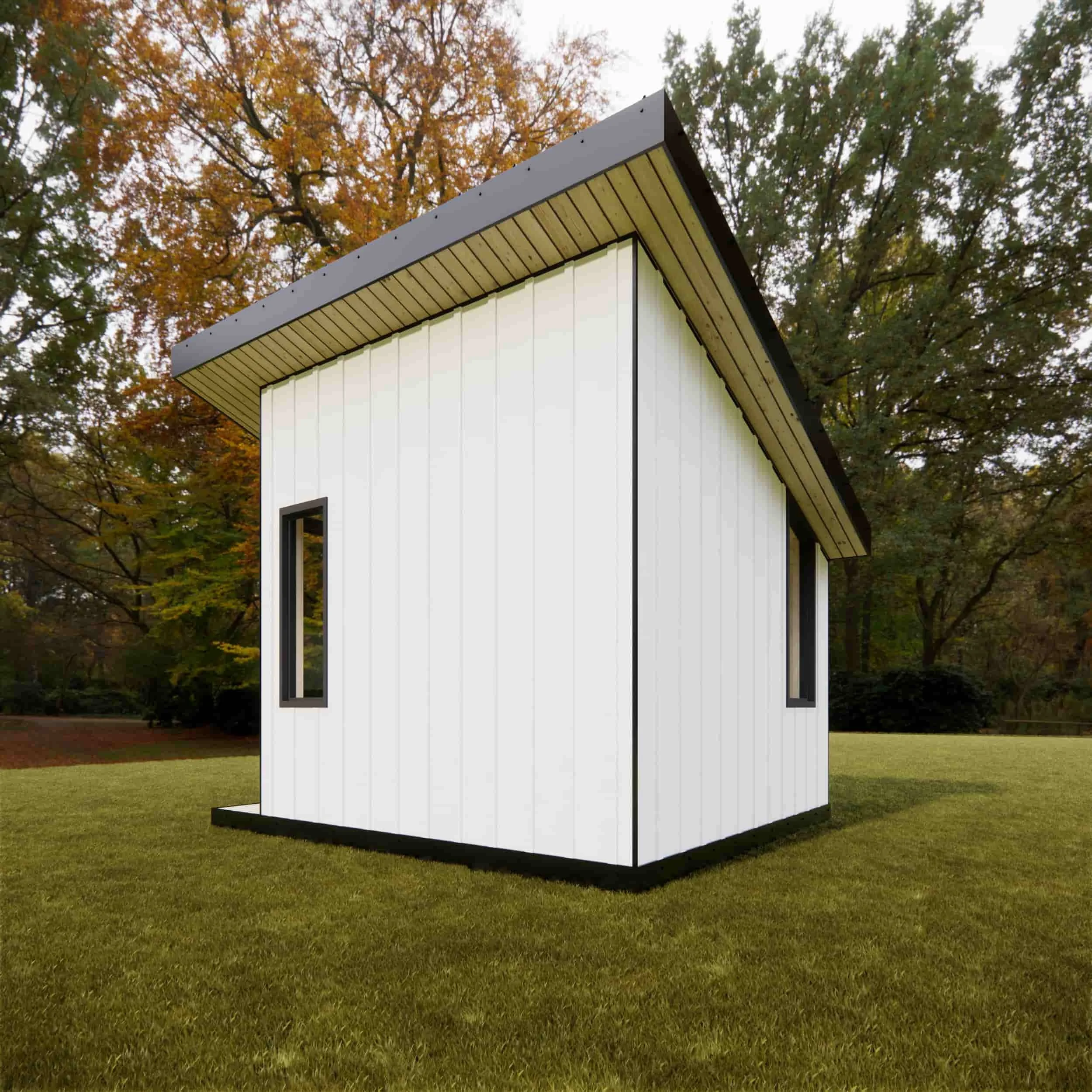 Small modern white house with black accents and a sloped roof, situated on a grassy lawn with autumn trees in the background.