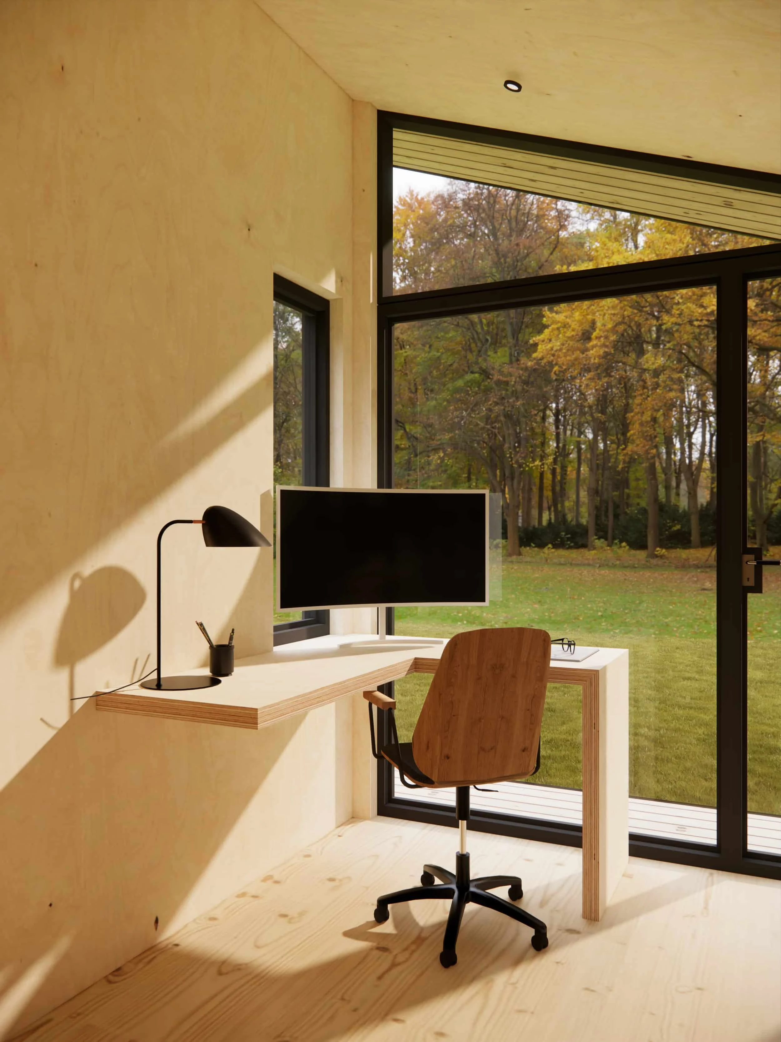 A minimalist home office with a wooden desk, black monitor, black desk lamp, messy pen holder, and wooden swivel chair. Large glass windows reveal a garden with trees in fall.