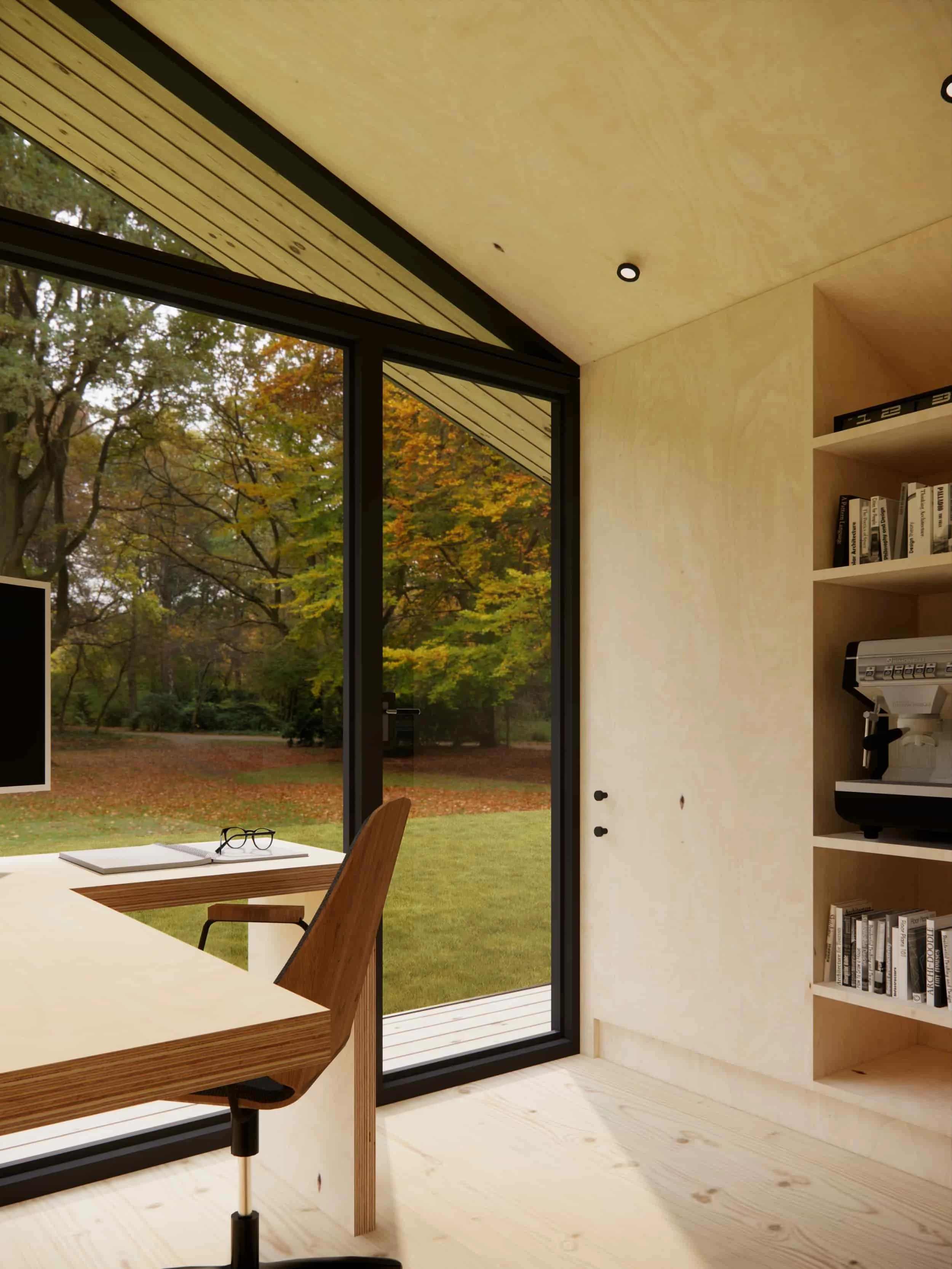 Modern indoor room with large glass sliding door revealing a yard with trees and autumn leaves outside. Features a wooden desk with a chair, a book, and glasses, and a built-in bookshelf with books and a coffee machine.