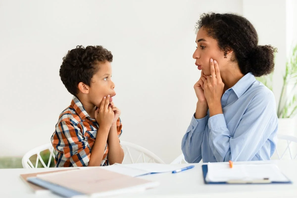 Child practicing language skills with speech therapist.