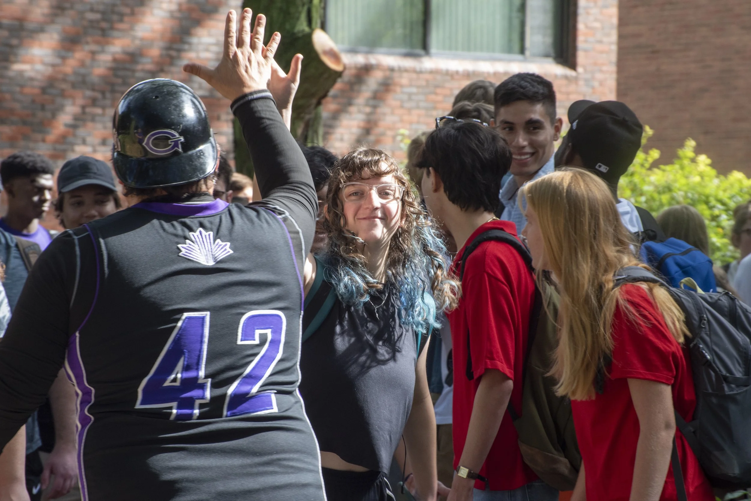 Jason Samuel, director of Globe Media, high fives sophomore Mackenzie Miller at Goshen College's annual applause tunnel.