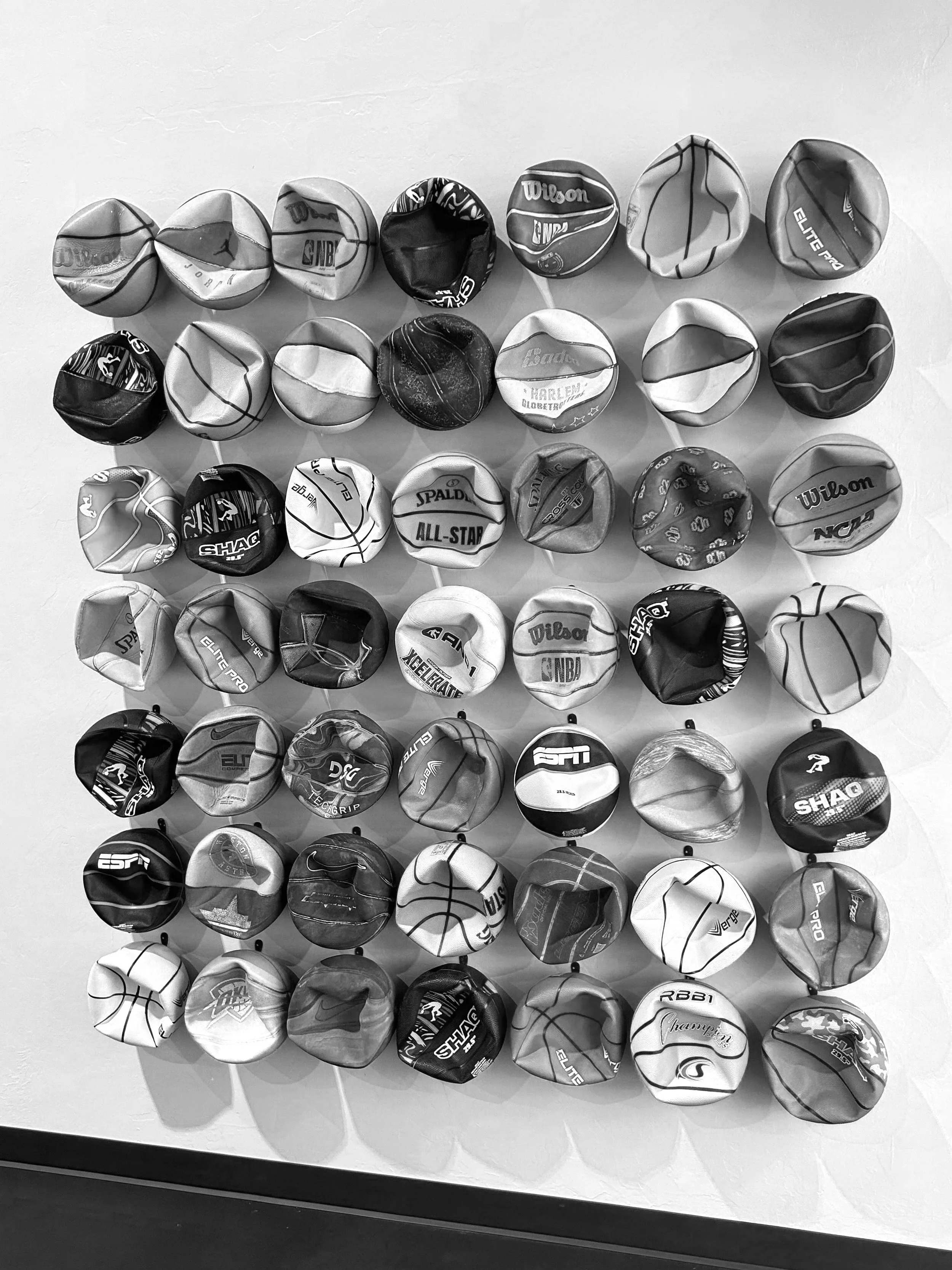 Collection of basketball balls arranged in a grid pattern on a white surface.