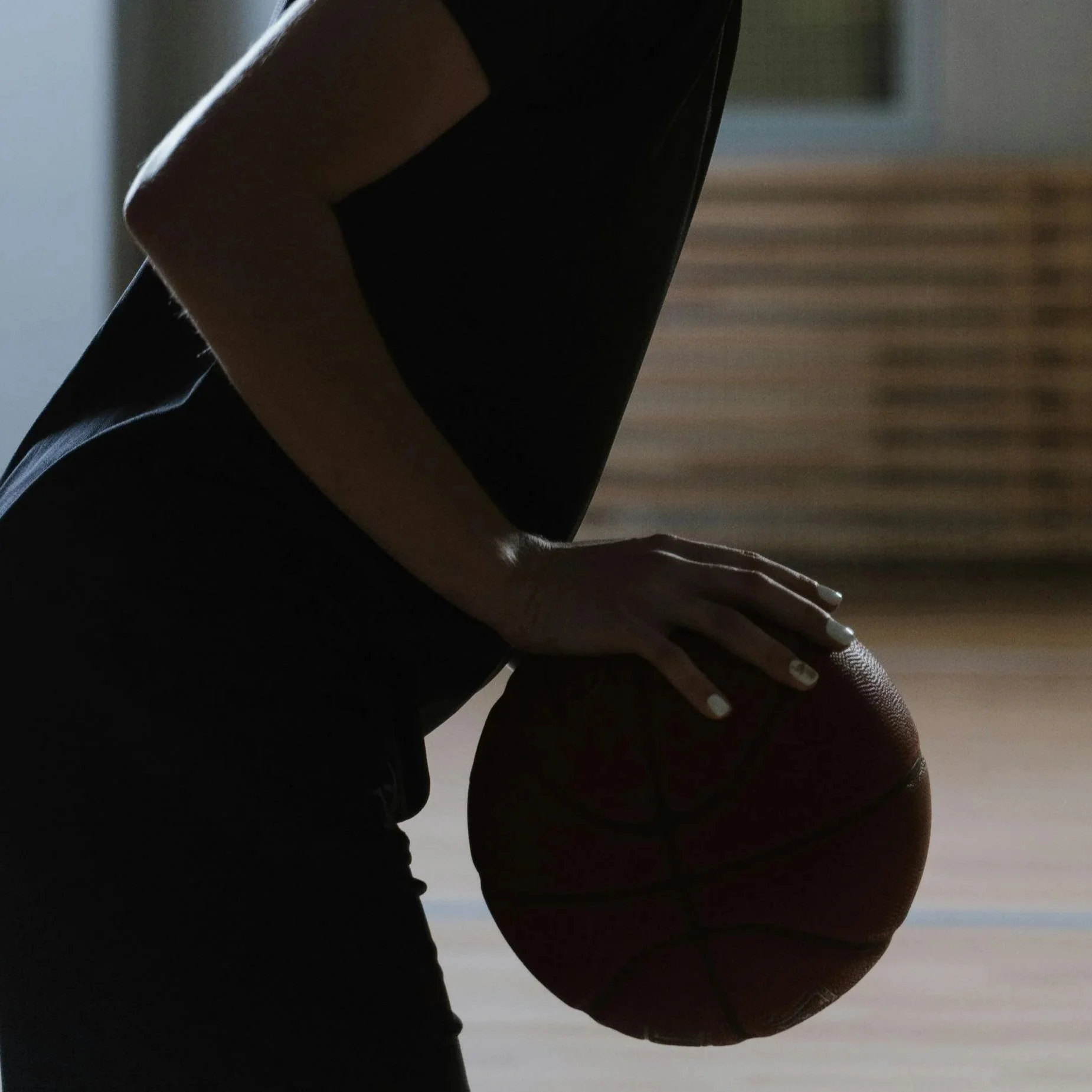 Person holding a basketball on an indoor court.