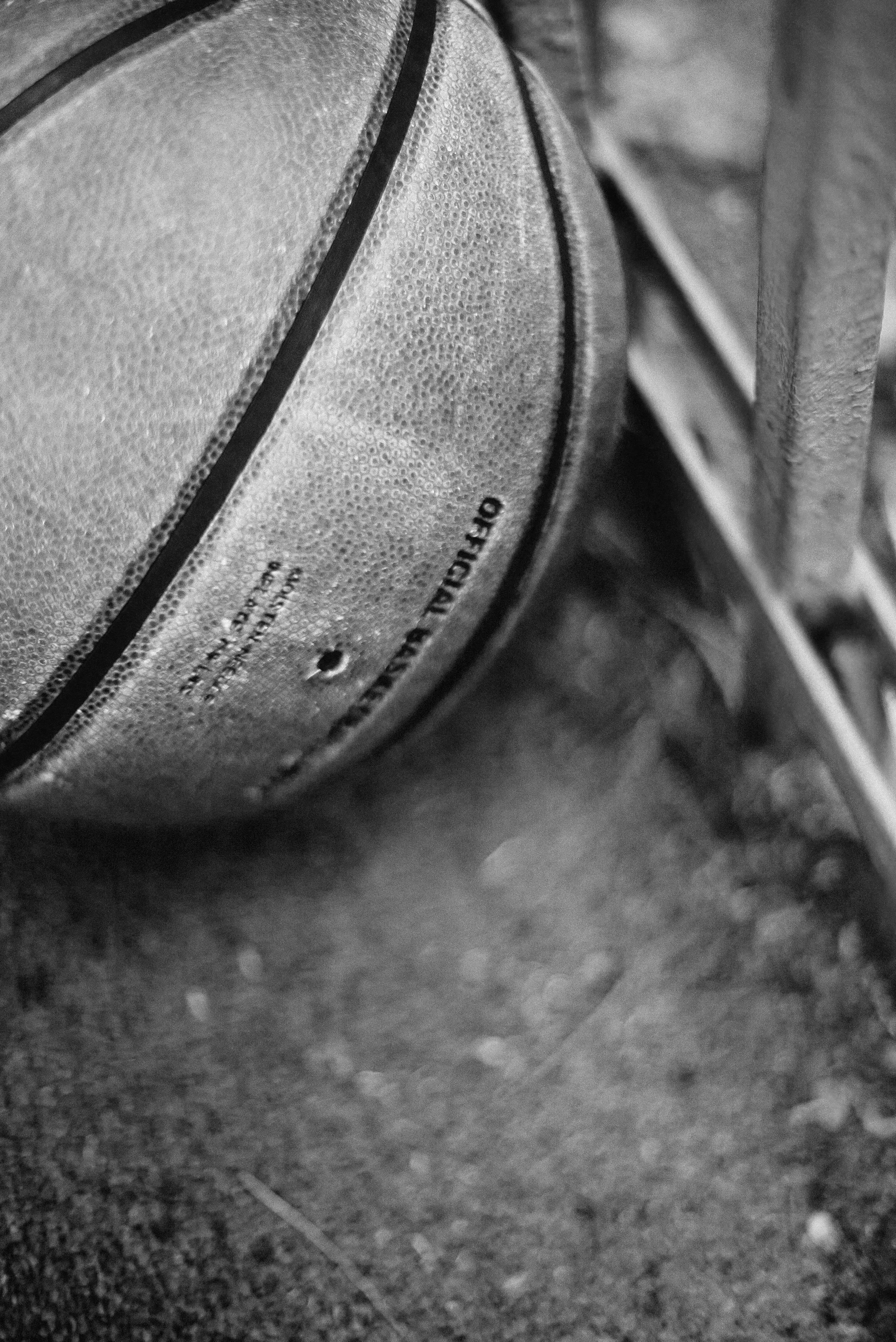 A gray basketball lying on a rough concrete surface, with the underside visible showing the words "Official Size" and "Indoor/Outdoor".