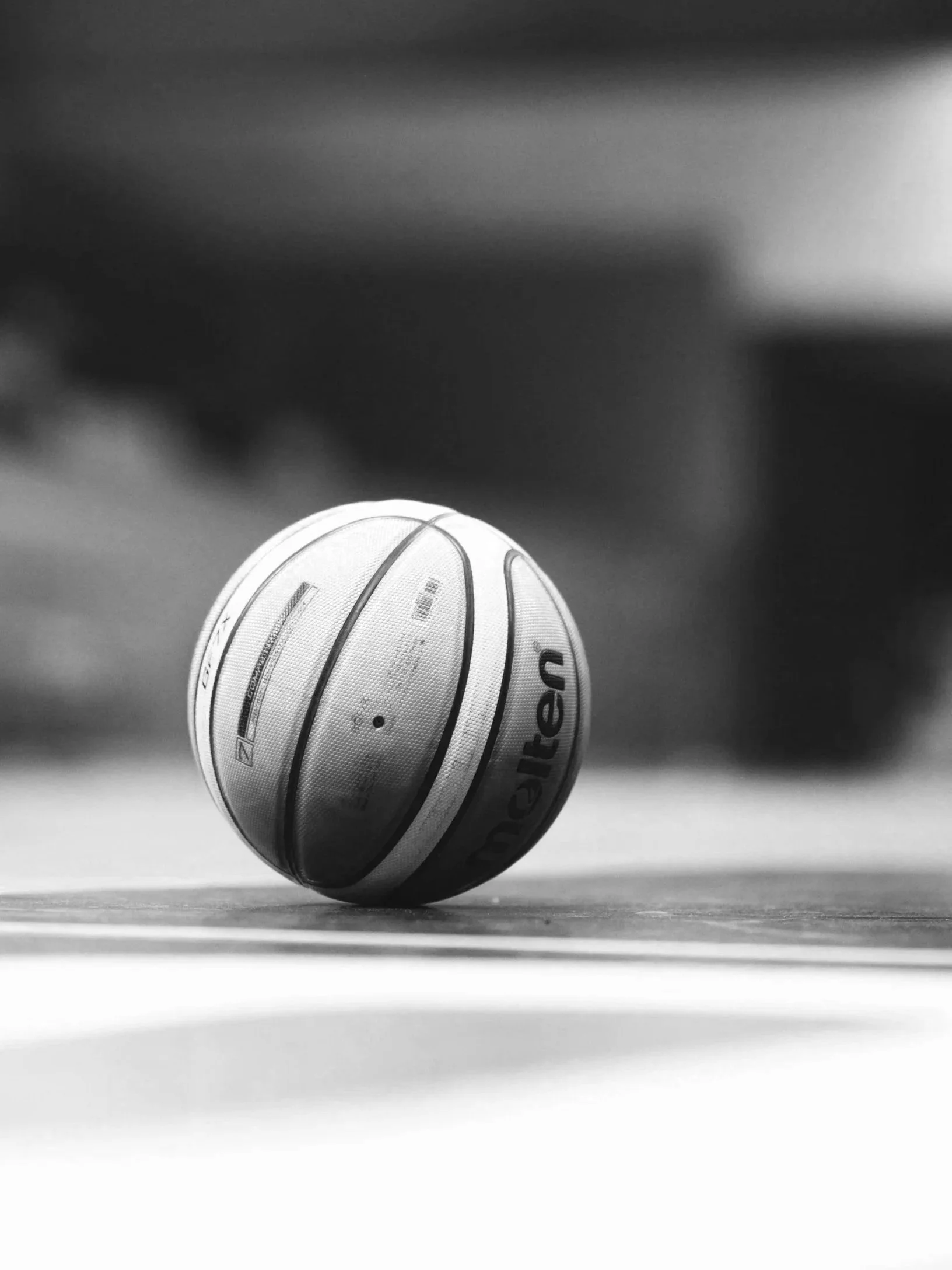 A close-up black-and-white photo of a basketball on a court surface