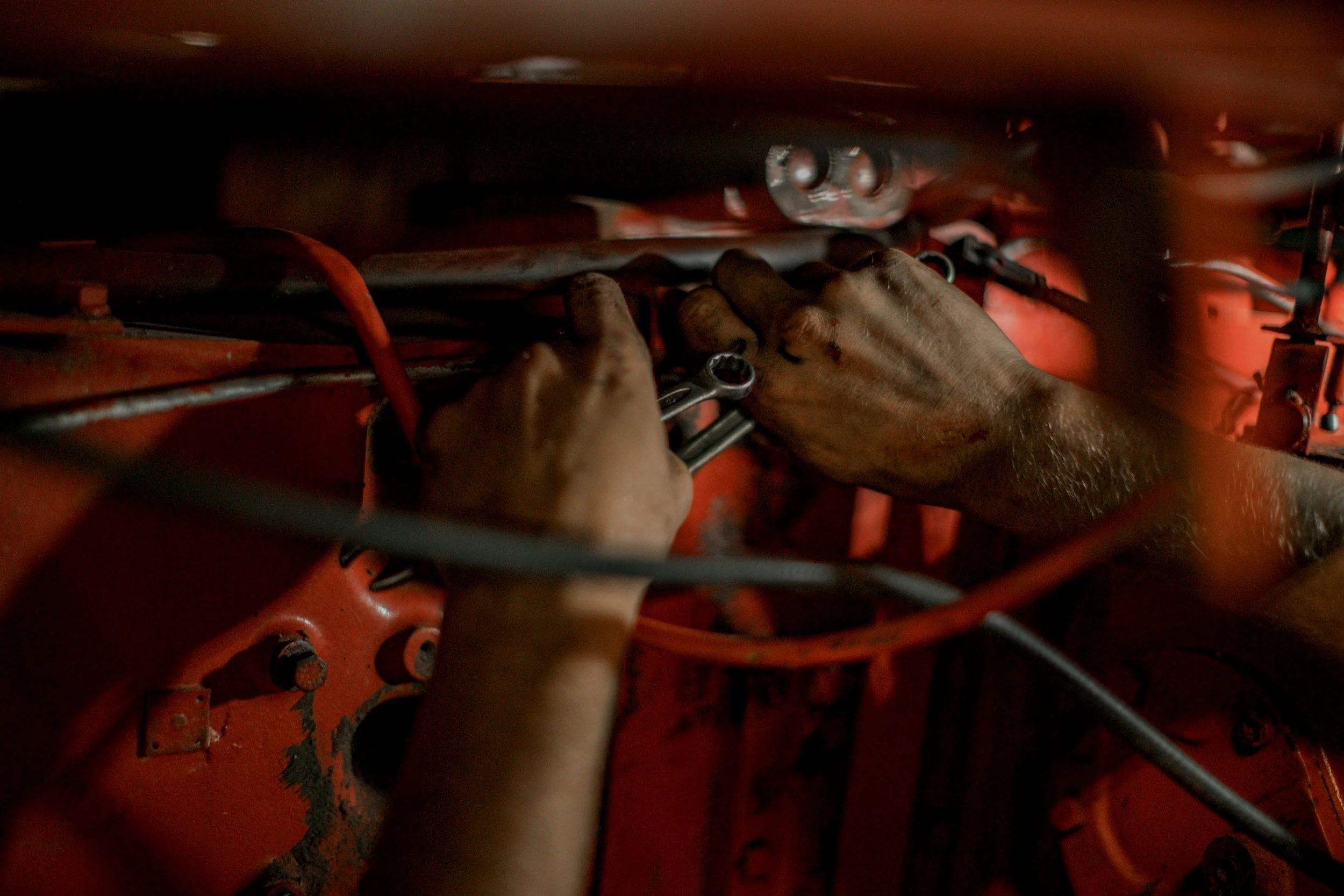 A person working with a wrench on an industrial machine with red and black components.