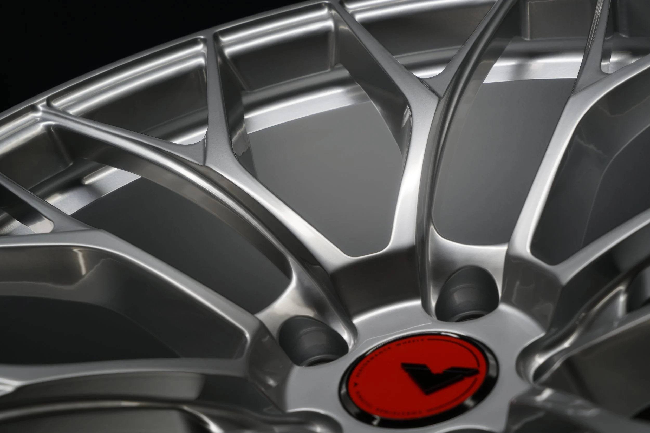 Close-up of a silver alloy car wheel with a red center cap featuring a black emblem.