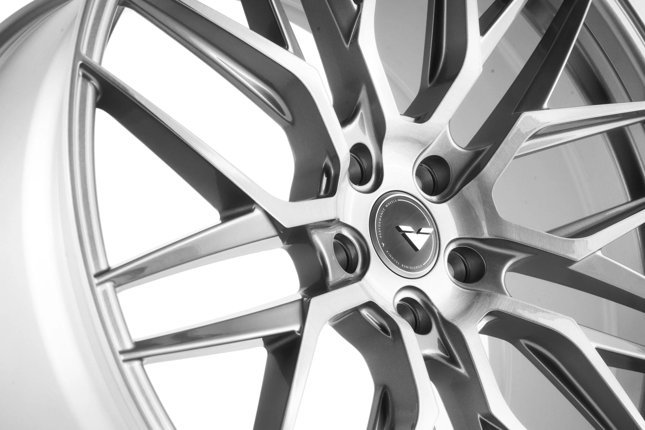 Close-up of a silver alloy wheel with a central hub displaying a logo, featuring multiple spokes in a modern design.