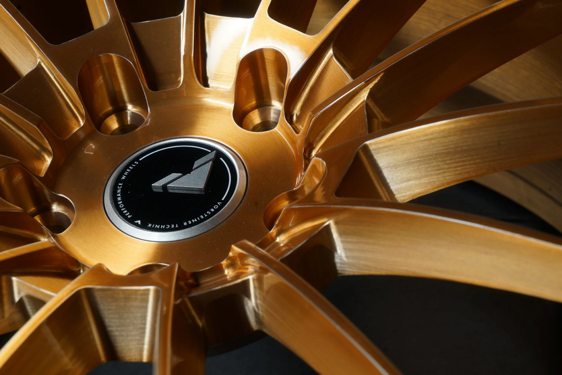 Close-up of a copper-colored alloy wheel with a black center cap featuring a stylized arrow and the words 'Performance Wheels' and 'Vortex Steering Technology'.