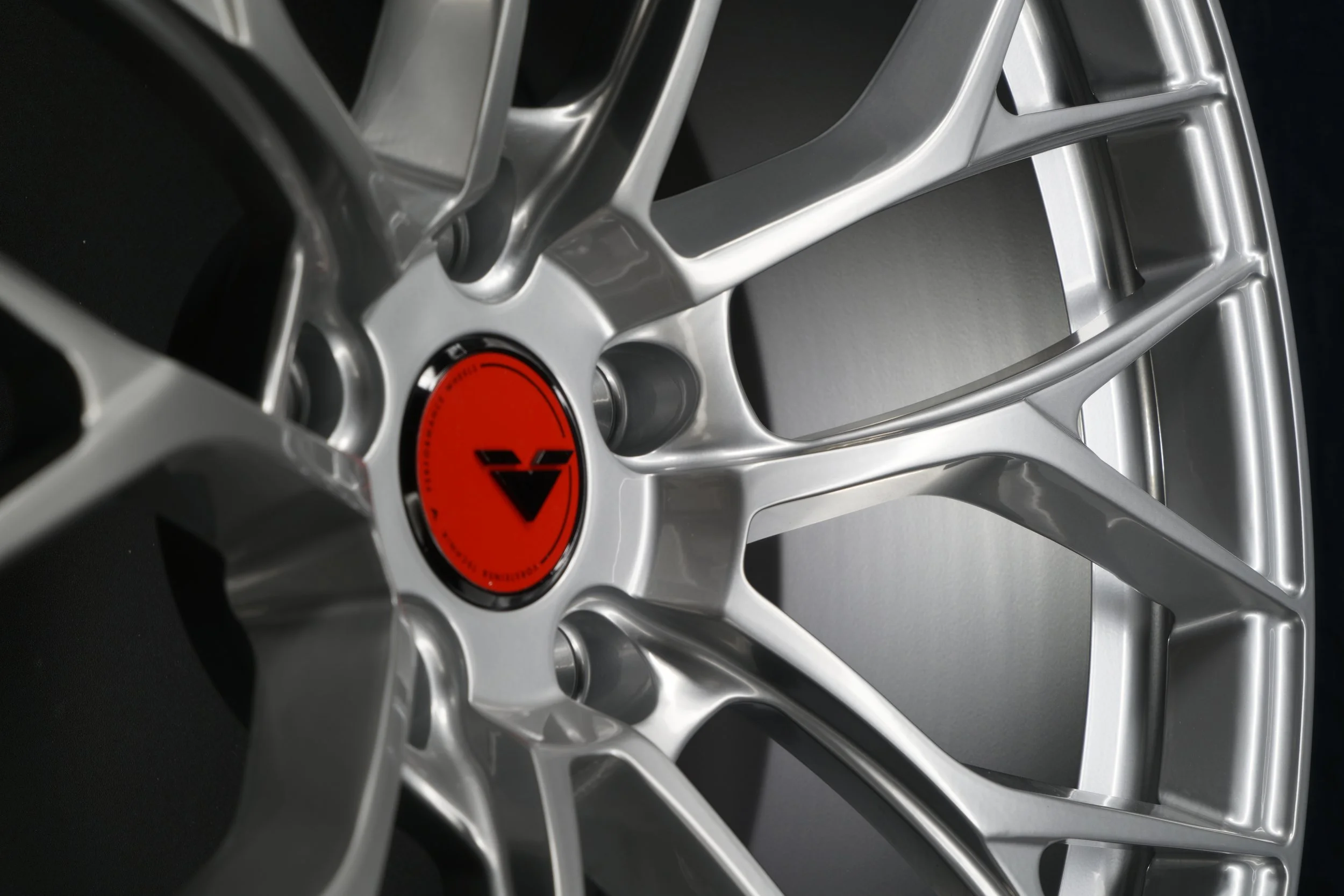 Close-up of a silver alloy wheel with a red center cap featuring a black triangular logo.