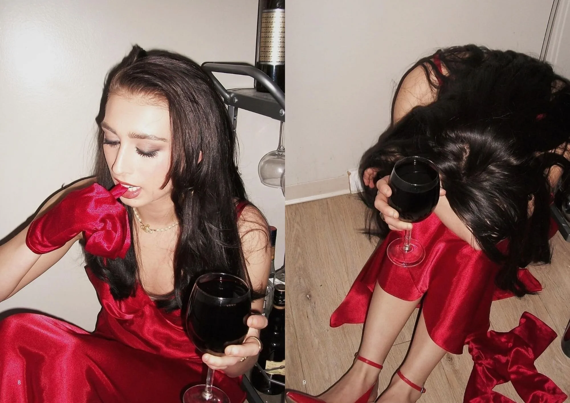 A woman with dark, wavy hair wearing a red satin dress with puffy sleeves, sitting on the floor with her eyes closed. She holds a glass of red wine in one hand and appears to be in a relaxed, contemplative state. There is a wine bottle, a wine glass,