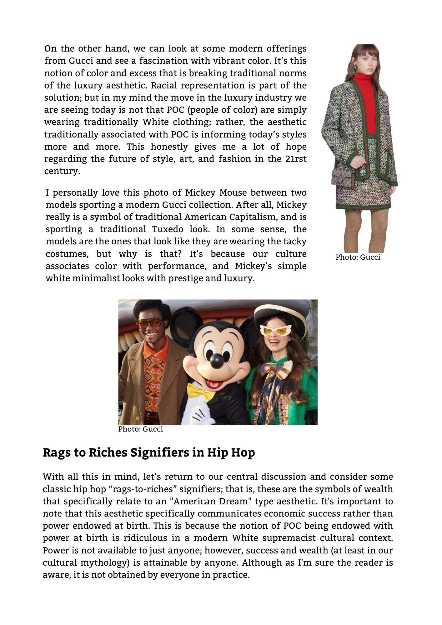 A person wearing a gray patterned jacket, red turtleneck, and green-trimmed gray skirt stands next to a woman in Disney's Mickey Mouse costume at a Disney theme park.