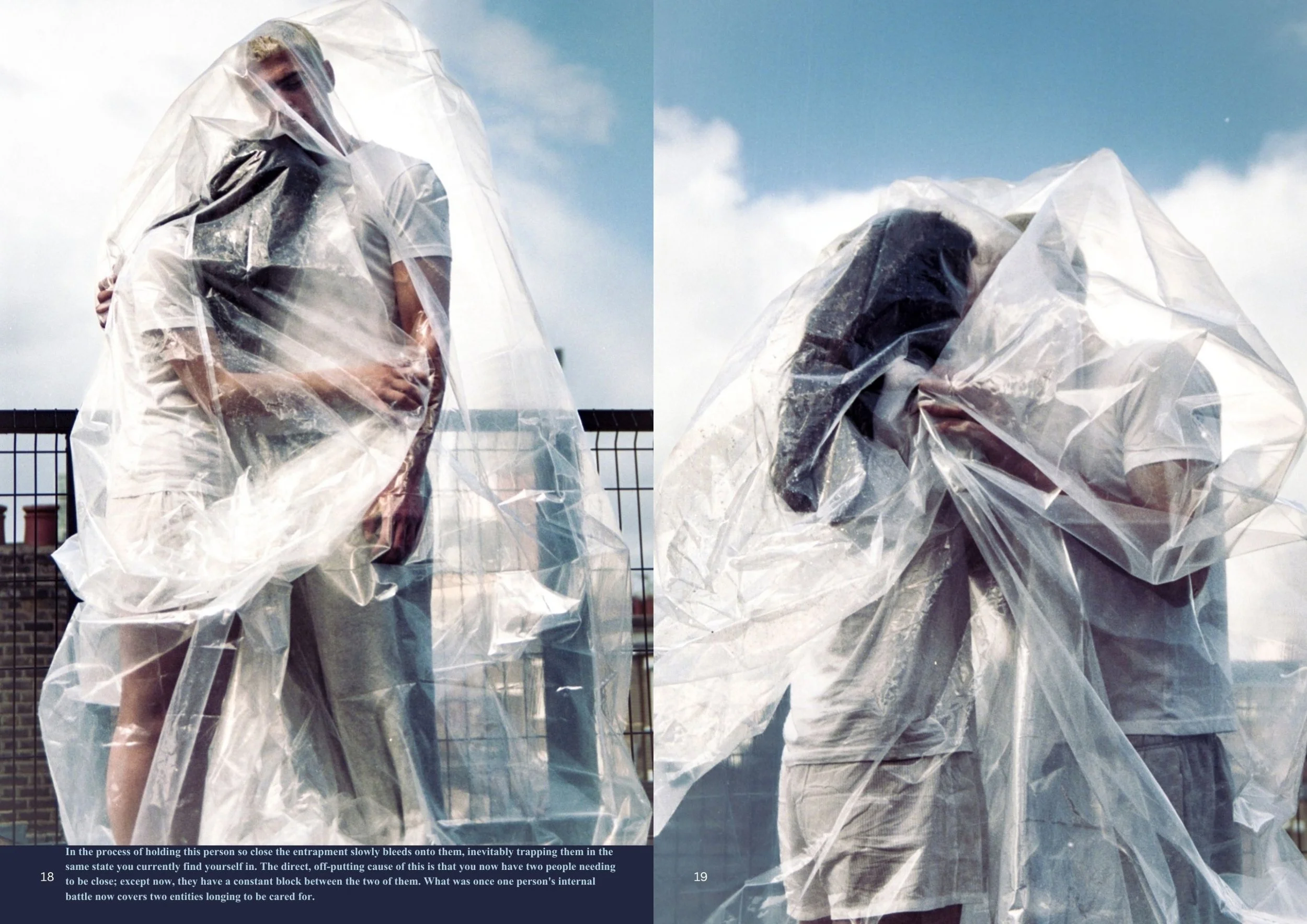 Two people wearing clear plastic ponchos are standing outdoors against a brick building and a metal fence, with a cloudy blue sky overhead.
