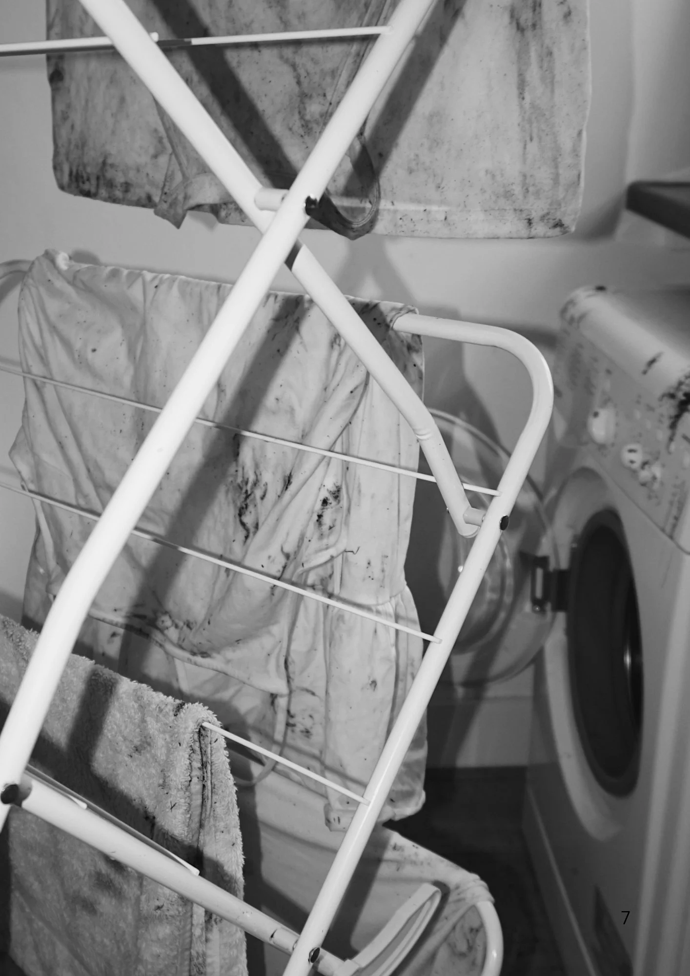 A laundry drying rack holding a piece of cloth, positioned in front of a washing machine.