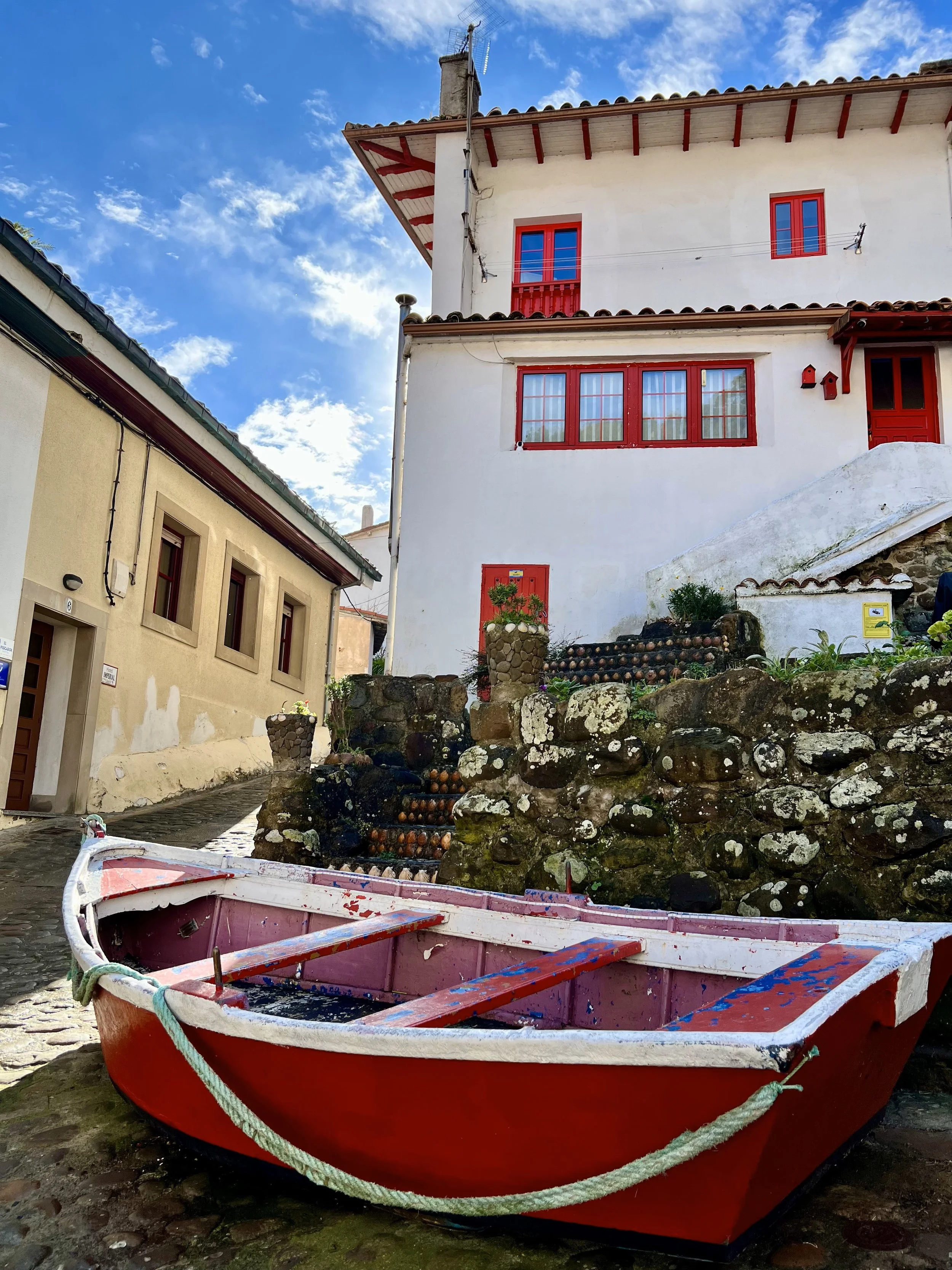 Photo of a red fishing boat in front of a house in Tazones