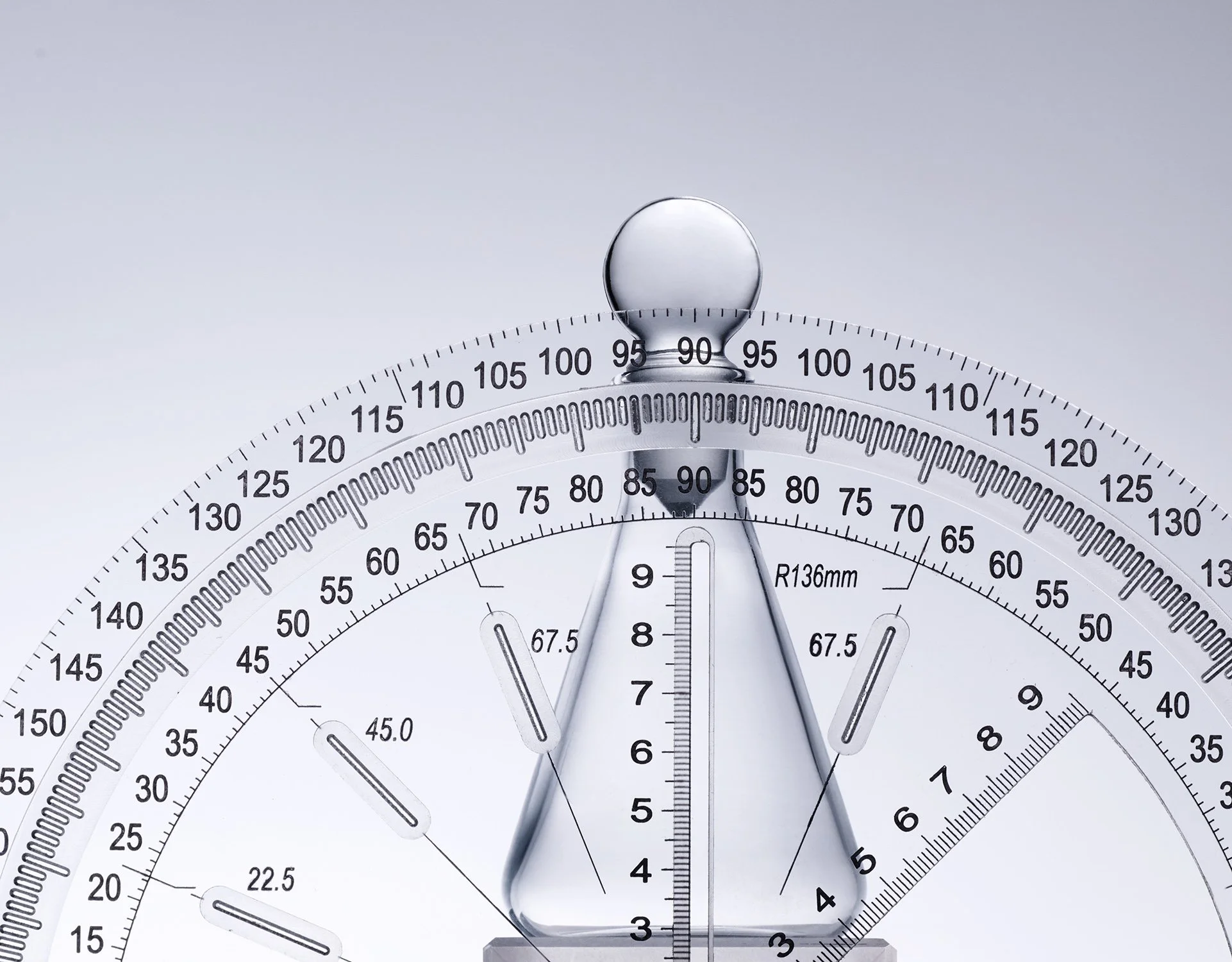 Close-up of a circular drafting or engineering compass with detailed measurement markings on a white background.