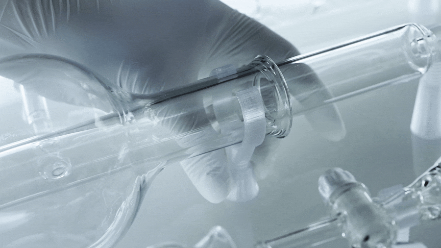 Close-up of a gloved hand holding a glass test tube in a laboratory setting.