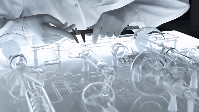 Scientist in gloves using calipers on glass laboratory equipment in a laboratory setting.