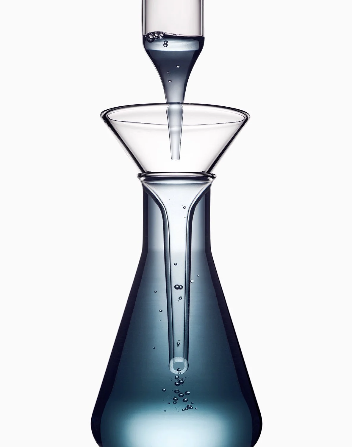Scientific glassware with water, including a large bottom flask, a long dropper, and two smaller funnels stacked on top.