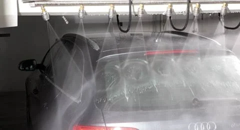 Car in a car wash with water spraying and brushes moving on the glass.