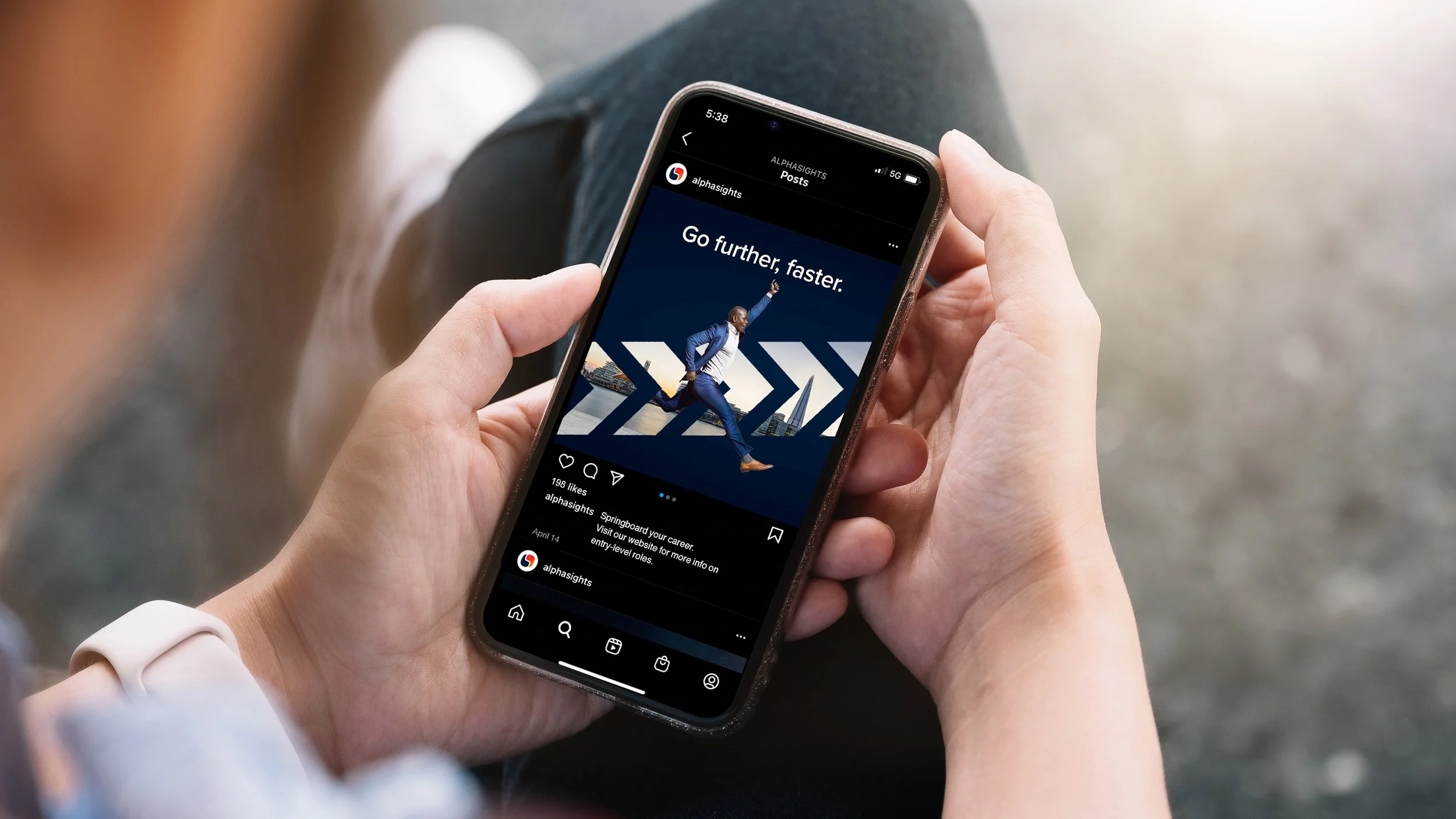 Person holding a smartphone displaying an Instagram post with a man in a suit running, with the text "Go further, faster."