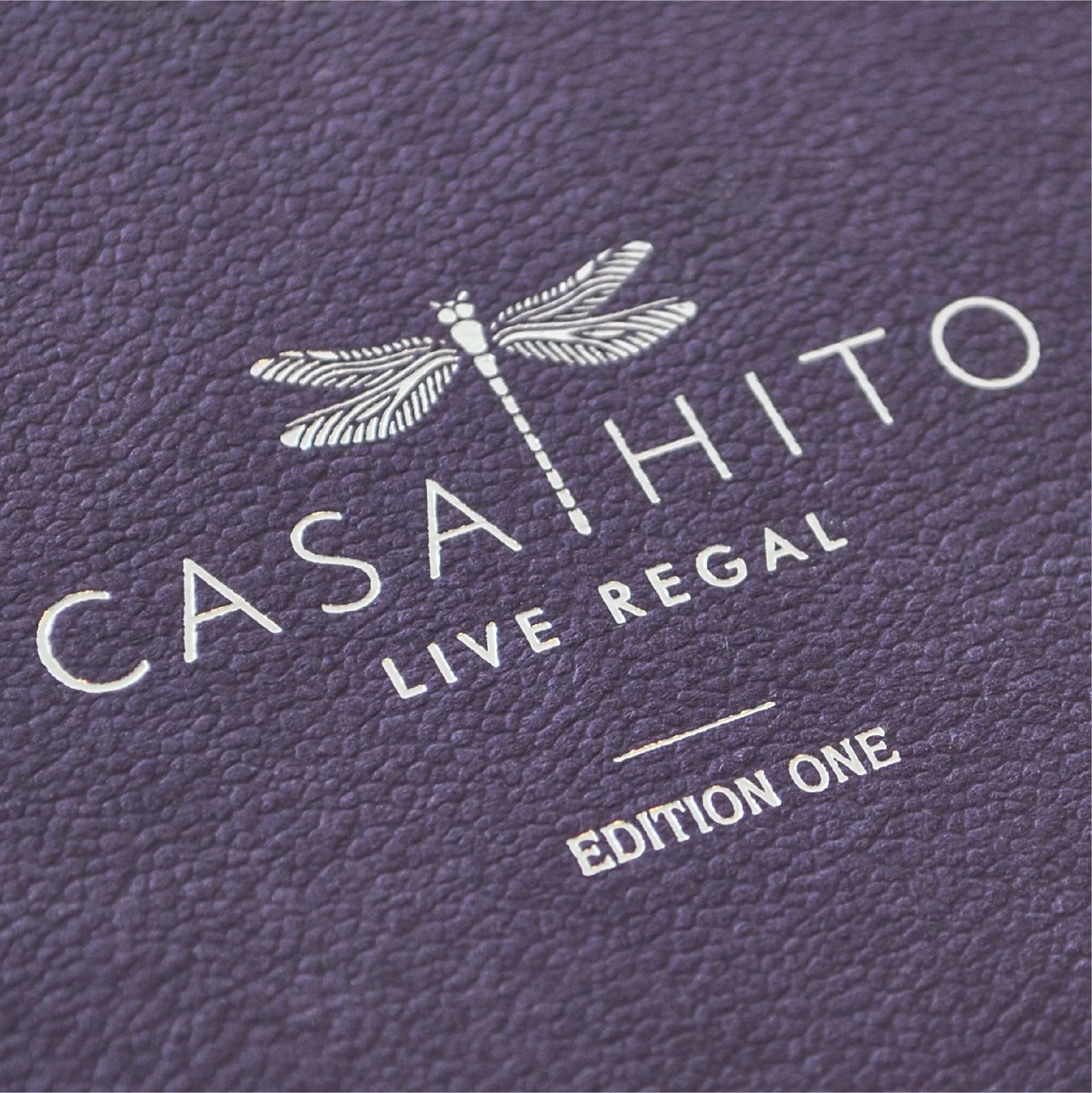 Casahito UK brand launch invitation featuring the dragonfly logo and 'Live Regal' tagline in silver foil on textured purple stock. A bespoke, haptic design piece created for the luxury home accessories market.