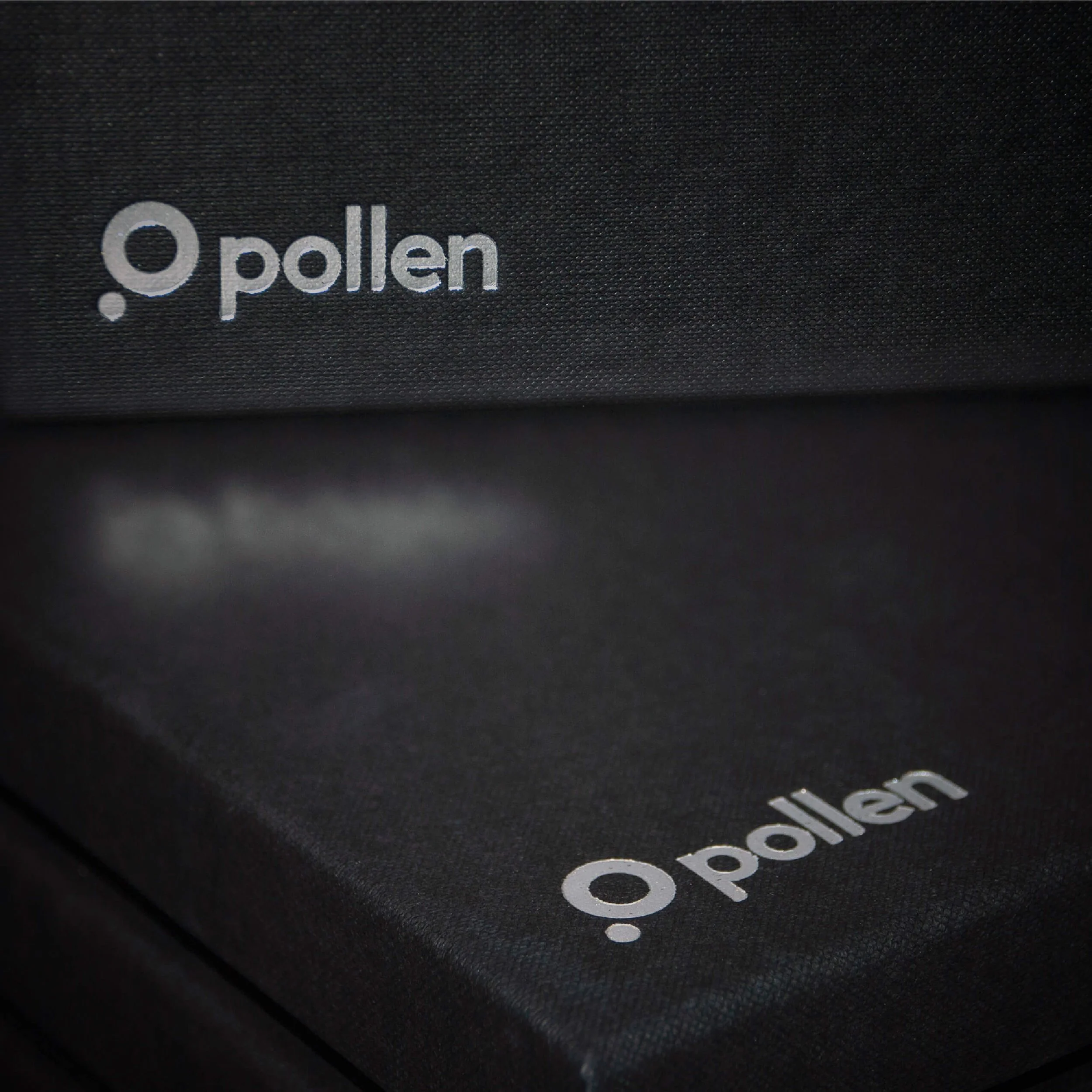 Close-up of black speakers with the white logo "pollen" on them.
