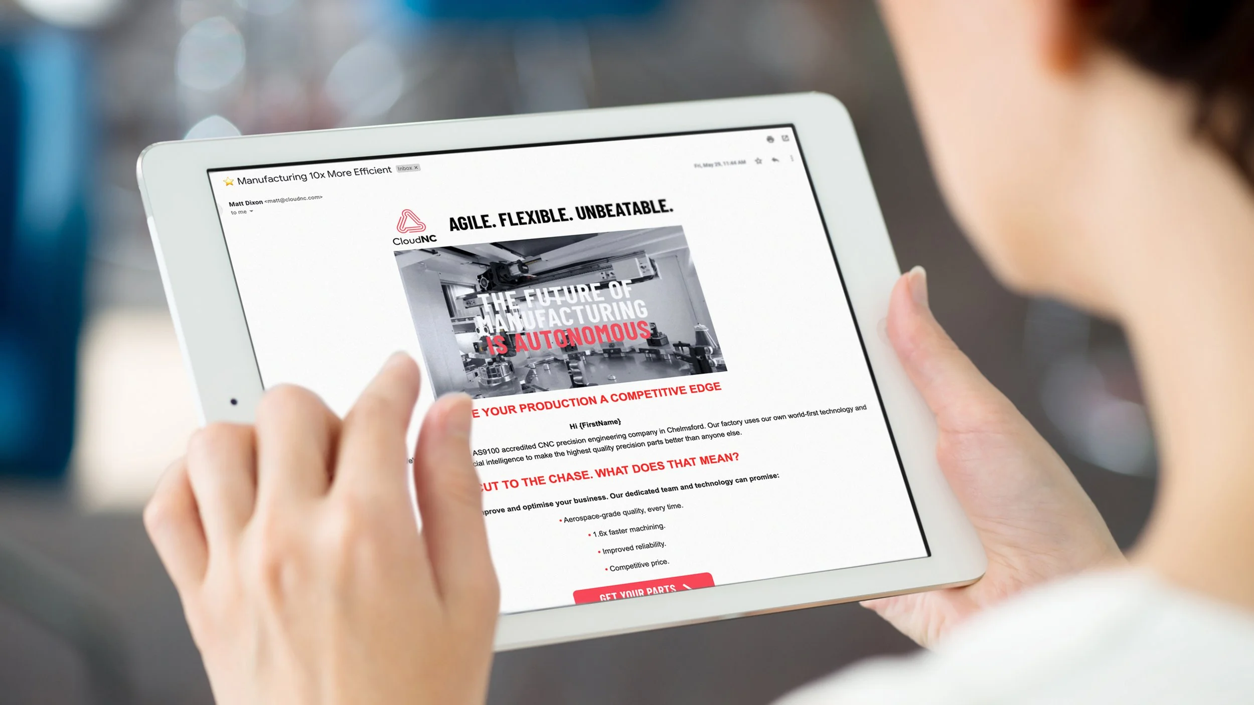 Person holding a tablet displaying an email or webpage about manufacturing automation, with text on the screen emphasizing agility, flexibility, and the future of manufacturing.
