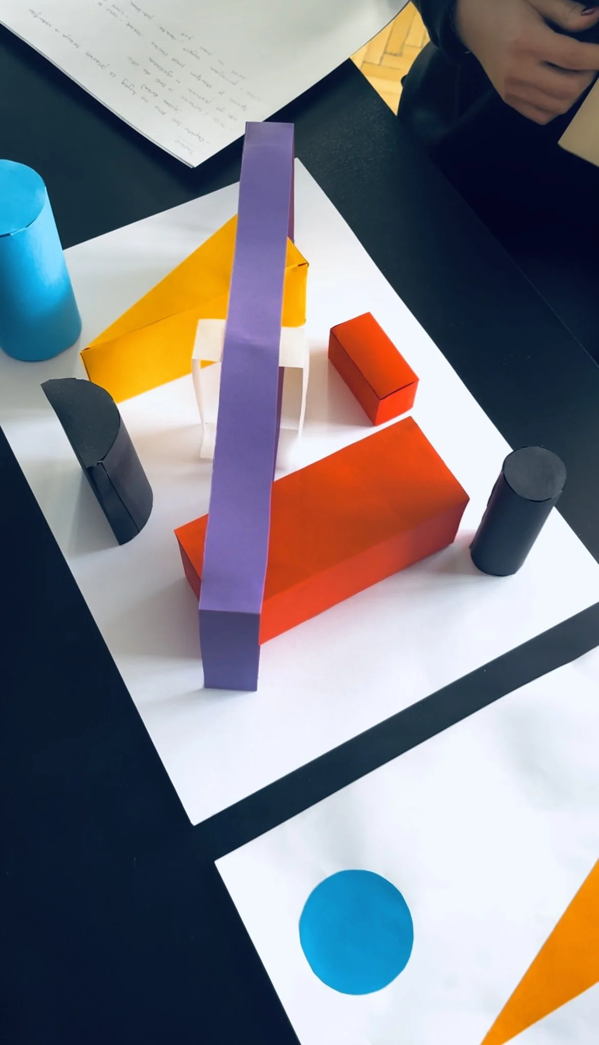 Radovi polaznika programa priprema za ŠPUD, Školu primjenjene umjetnosti i dizajna u Zagrebu.
Colorful architectural model with geometric shapes, including cylinders, rectangles, and a long purple ramp, on a black and white surface.