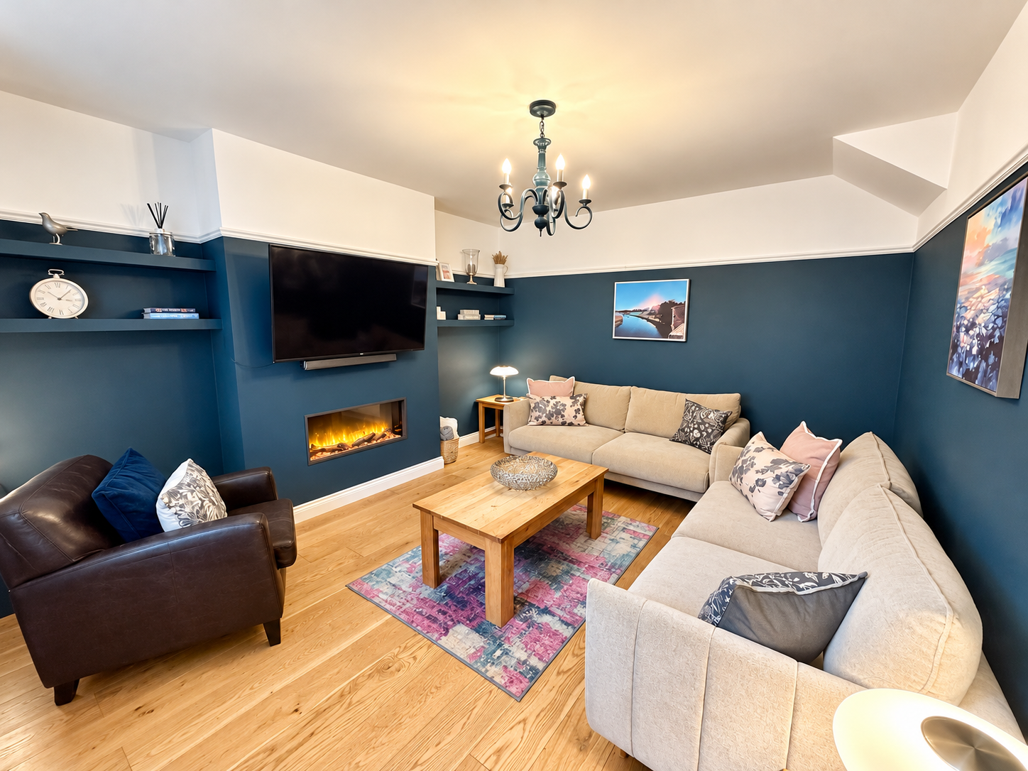 Stylish lounge at Castle Walk House holiday cottage in Alnwick, featuring two comfortable sofas, a leather armchair, feature fireplace and Smart TV.