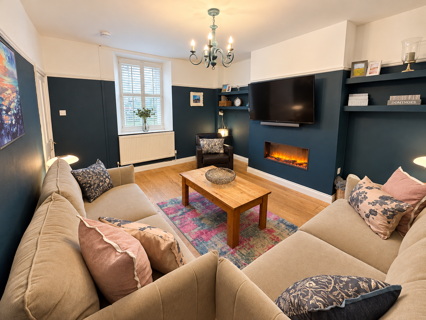 Stylish lounge at Castle Walk House holiday cottage in Alnwick, featuring two comfortable sofas, a leather armchair, feature fireplace and Smart TV.