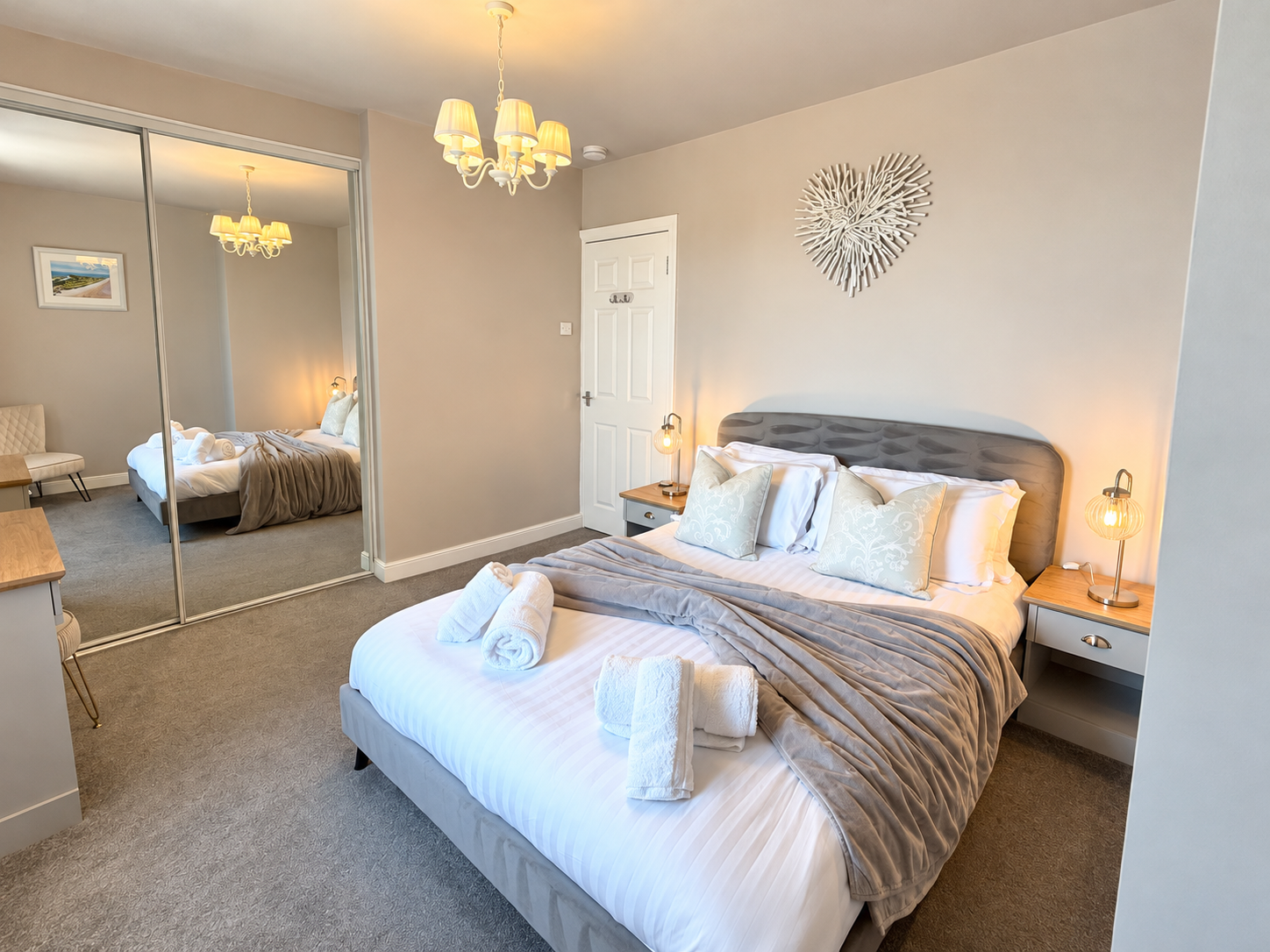 Spacious king-size bedroom at The Sands Cottage in Seahouses, featuring a comfortable pocket-sprung mattress, mirrored wardrobes, bedside lighting and elegant neutral décor.