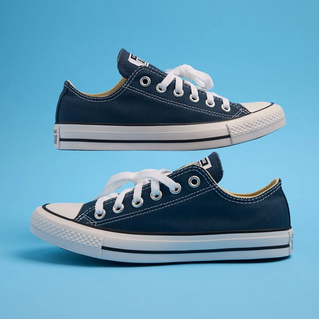 Pair of navy blue canvas sneakers with white soles and laces, stacked against a blue background.