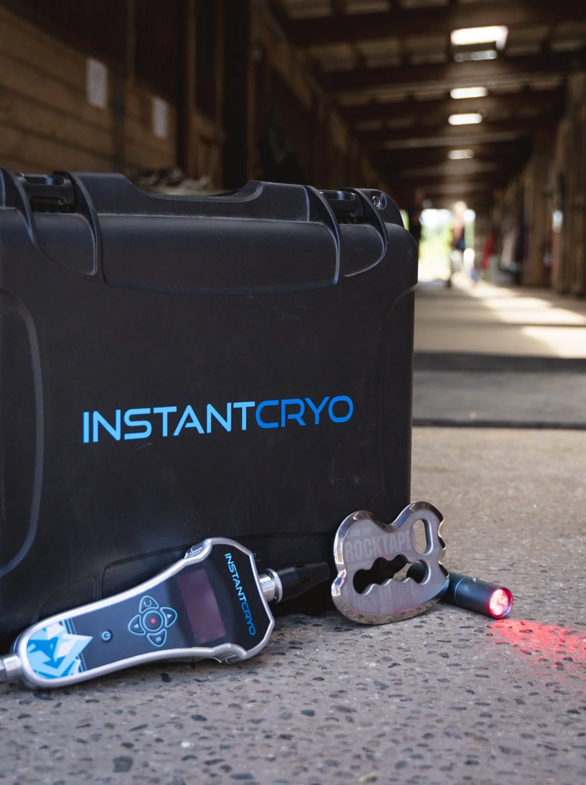 A black INSTANTCRYO™ box sits on the floor of a stables, with the Cryotherapy machine and tools next to it.