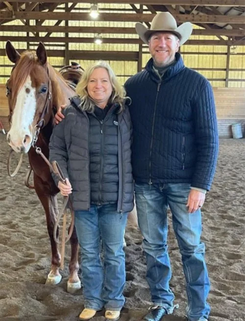 Tammie holds one of her horses and stands with multiple world and national champion show horse trainer Mark Shaffer
