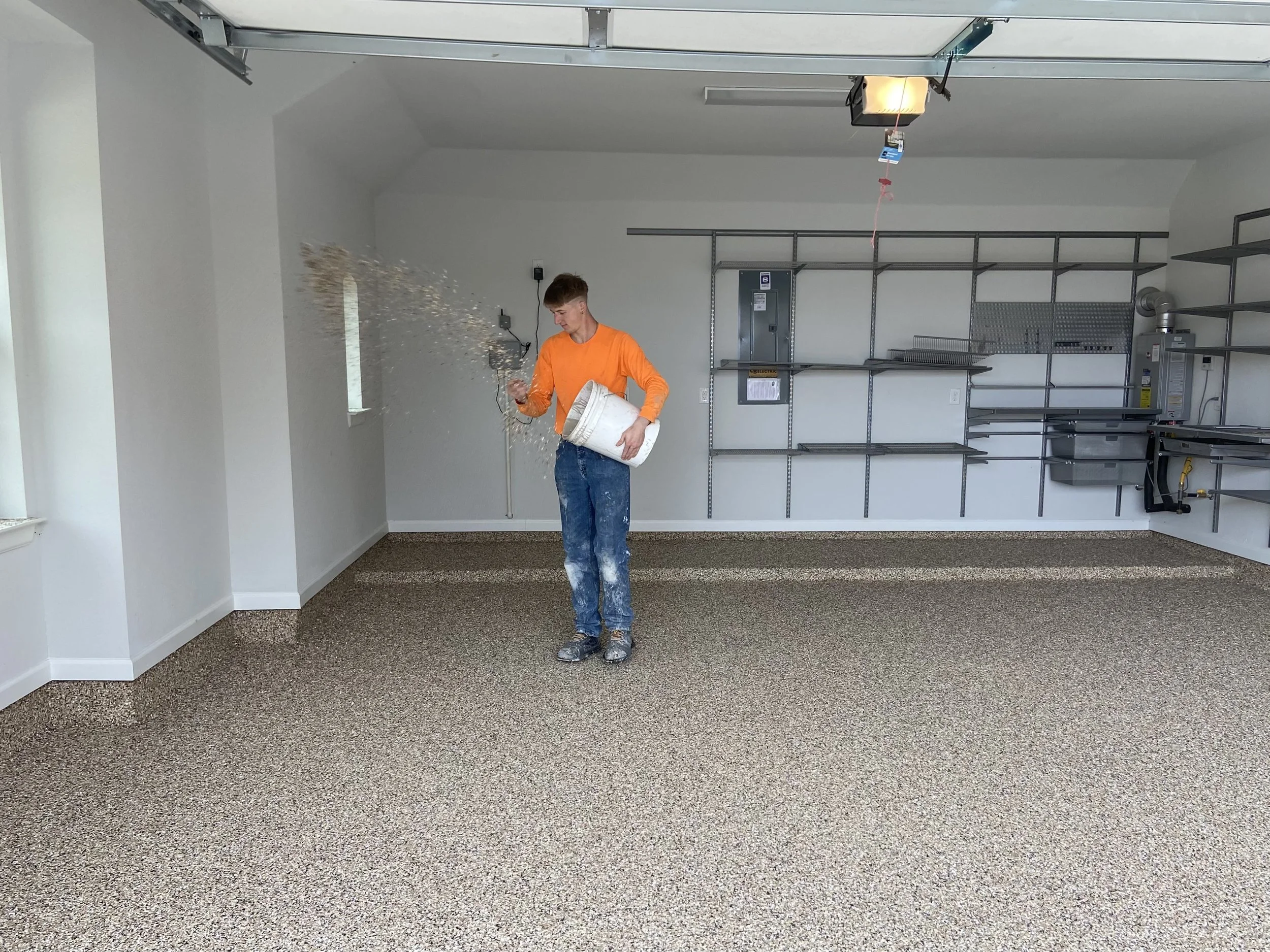 Person applying decorative flakes to an epoxy garage floor