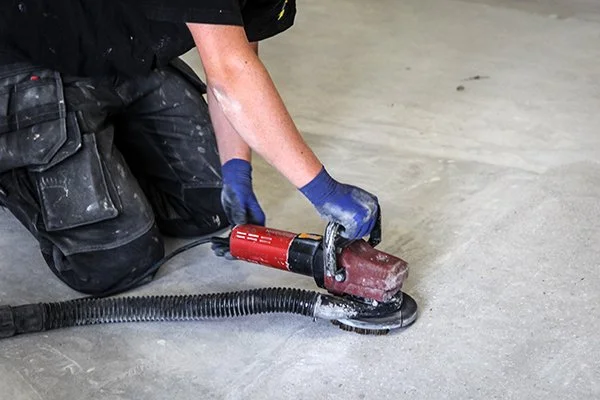 Person using a floor grinding machine in a garage