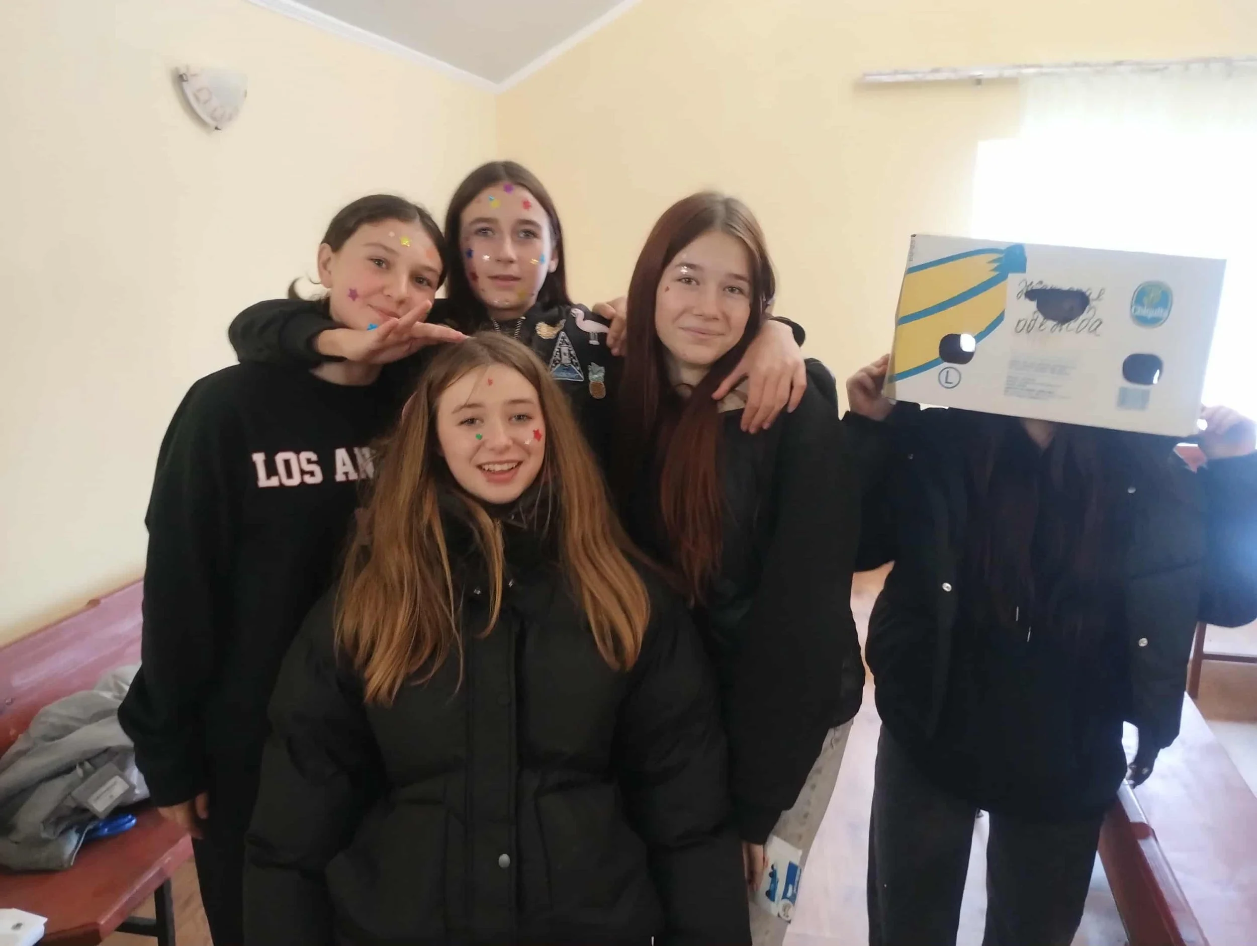 Five young women standing close together in a room, smiling at the camera